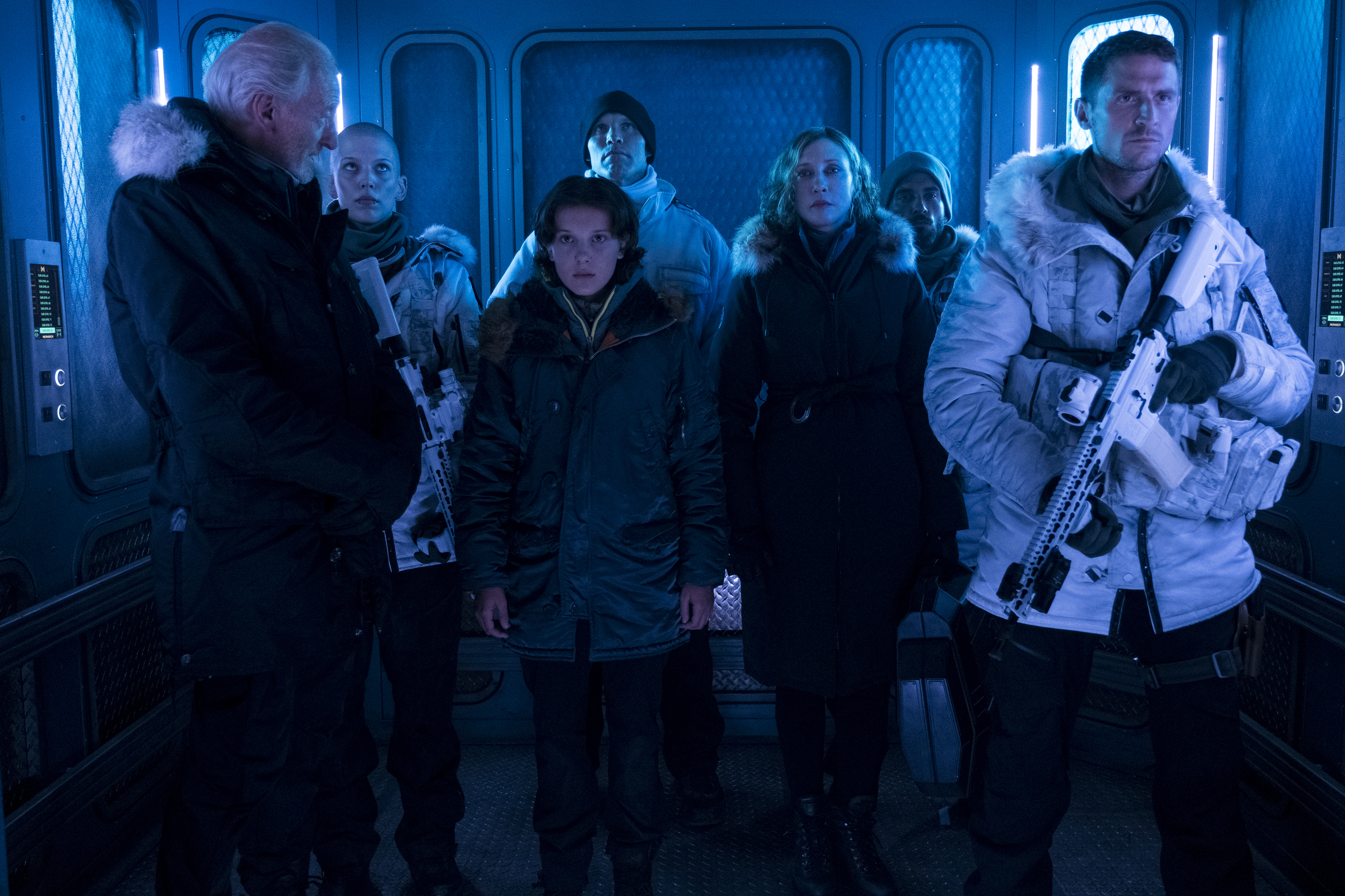 Group of people in winter gear inside a spaceship HD Wallpaper