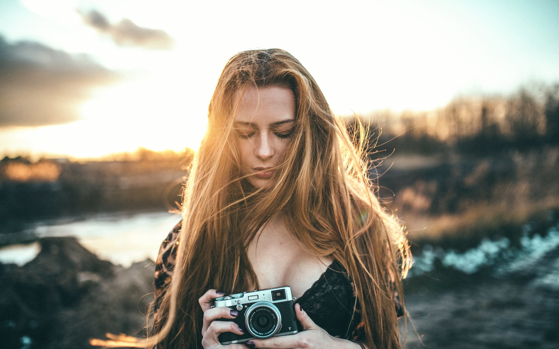 Woman holding a camera at sunset HD Wallpaper