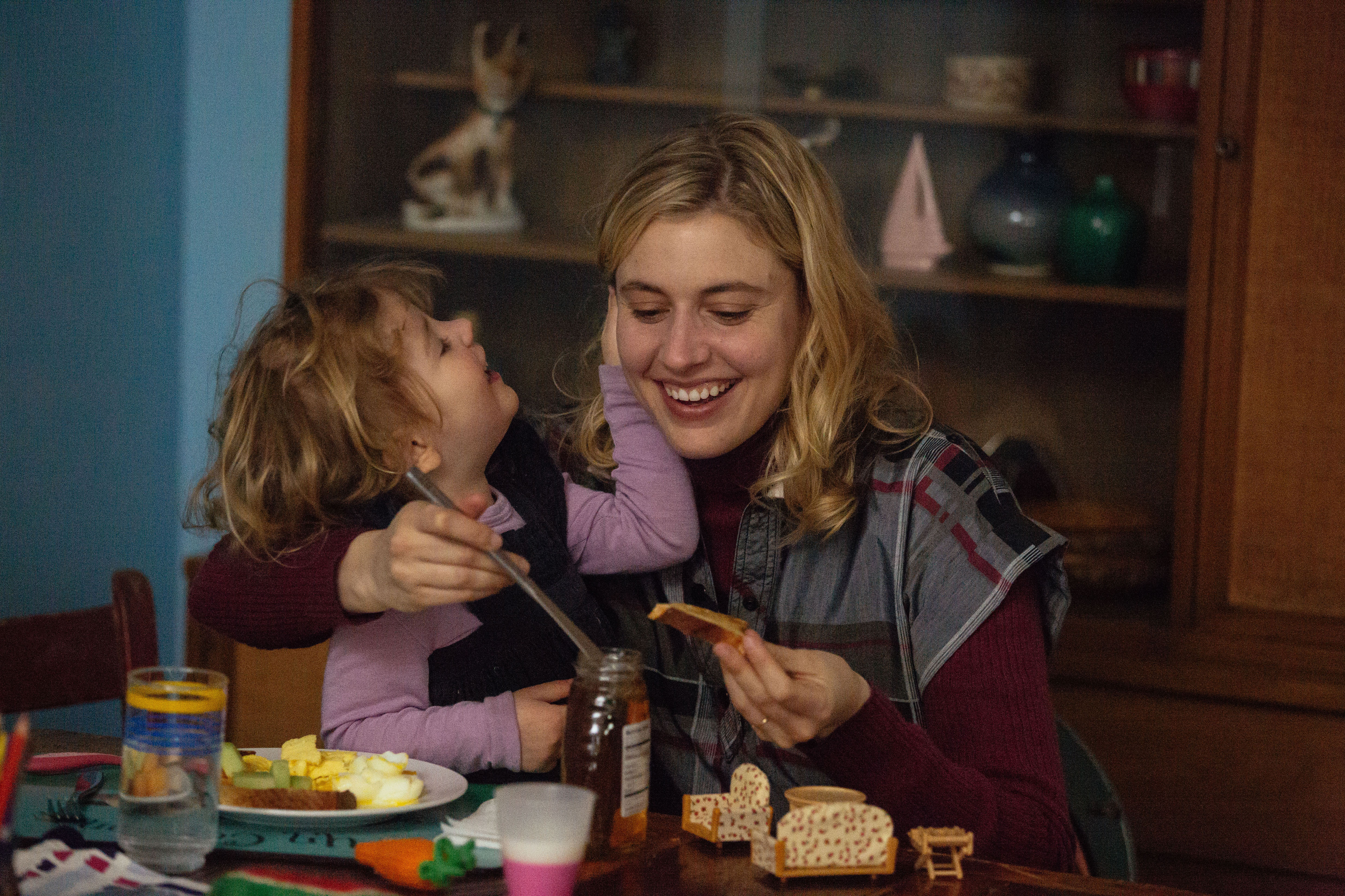 Greta Gerwig with a child at a table HD Wallpaper