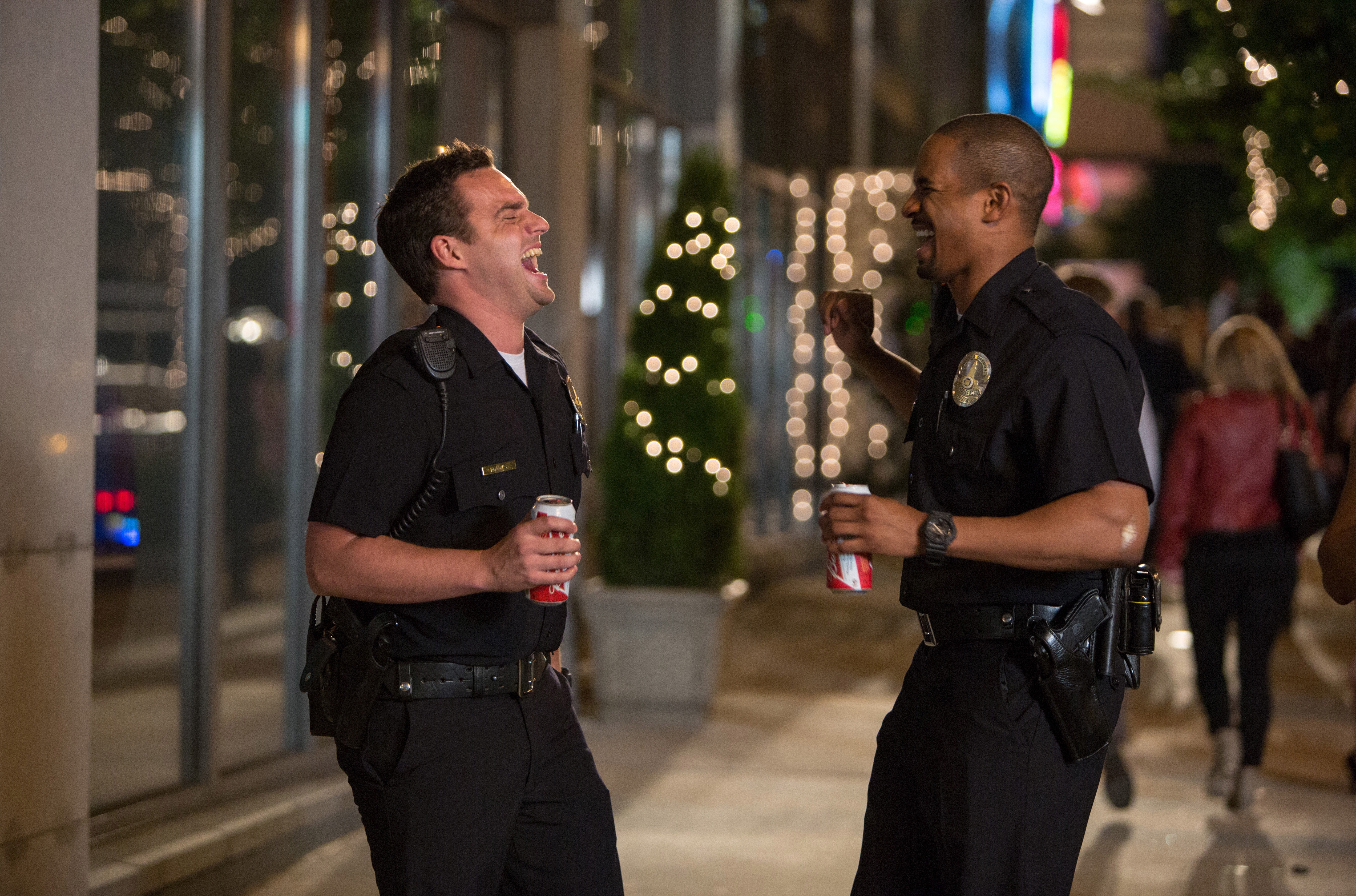 Two police officers laughing and holding cans HD Wallpaper