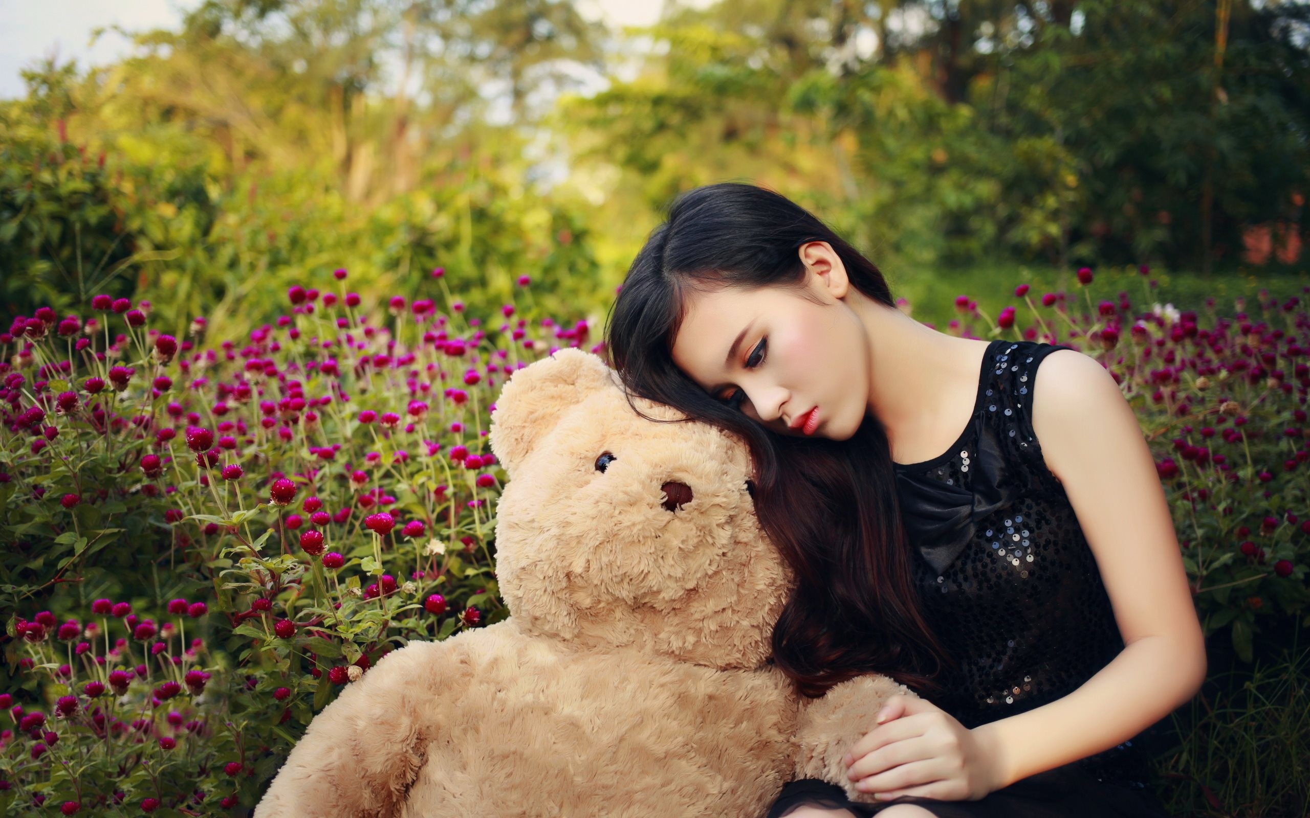 Girl resting head on teddy bear in flower garden HD Wallpaper