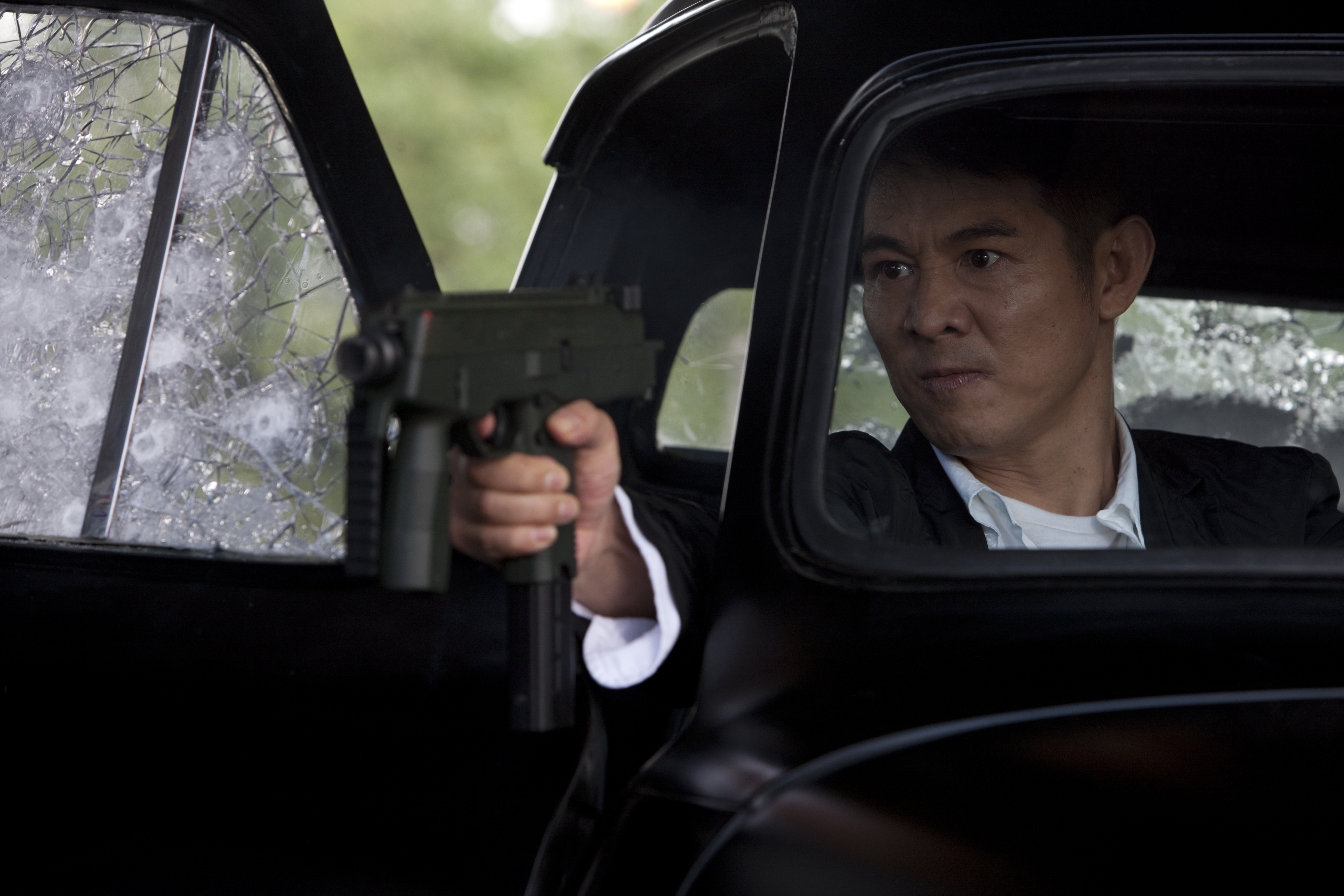 Jet Li in a car holding a gun HD Wallpaper