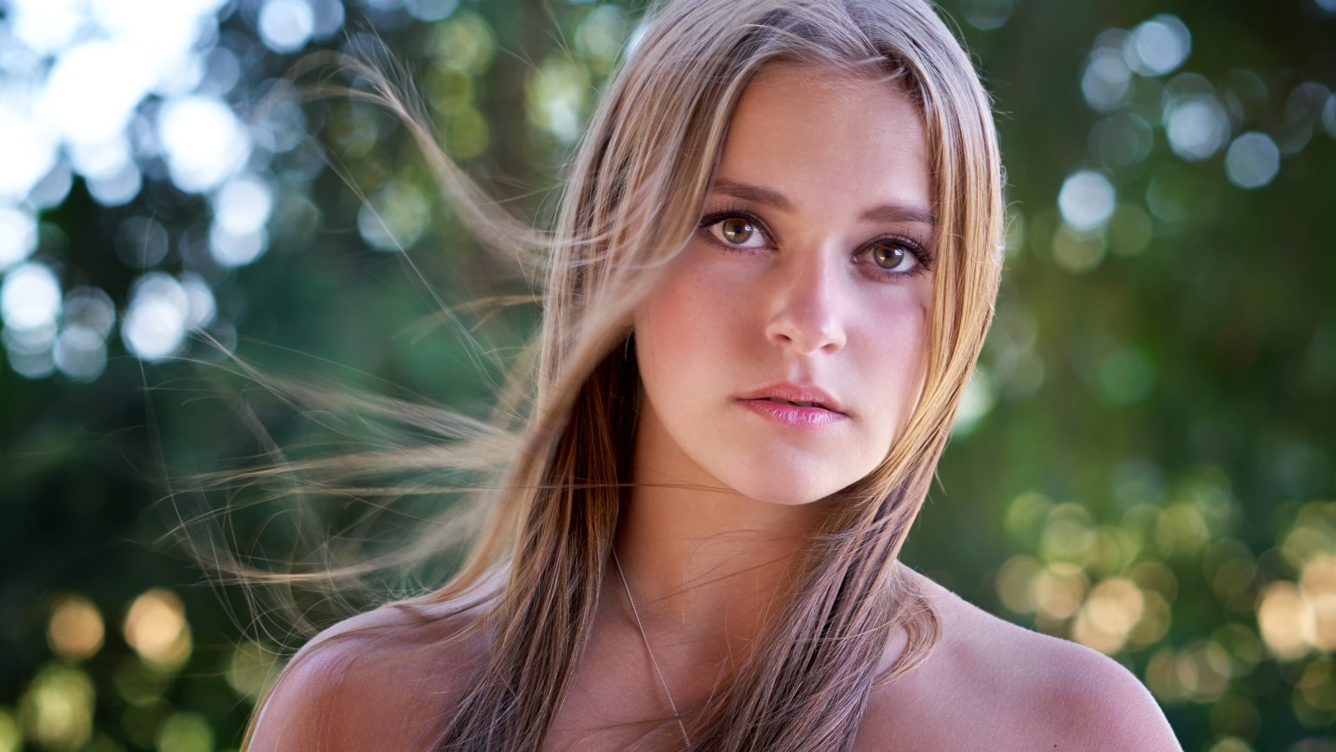 Young woman with windblown hair outdoors HD Wallpaper