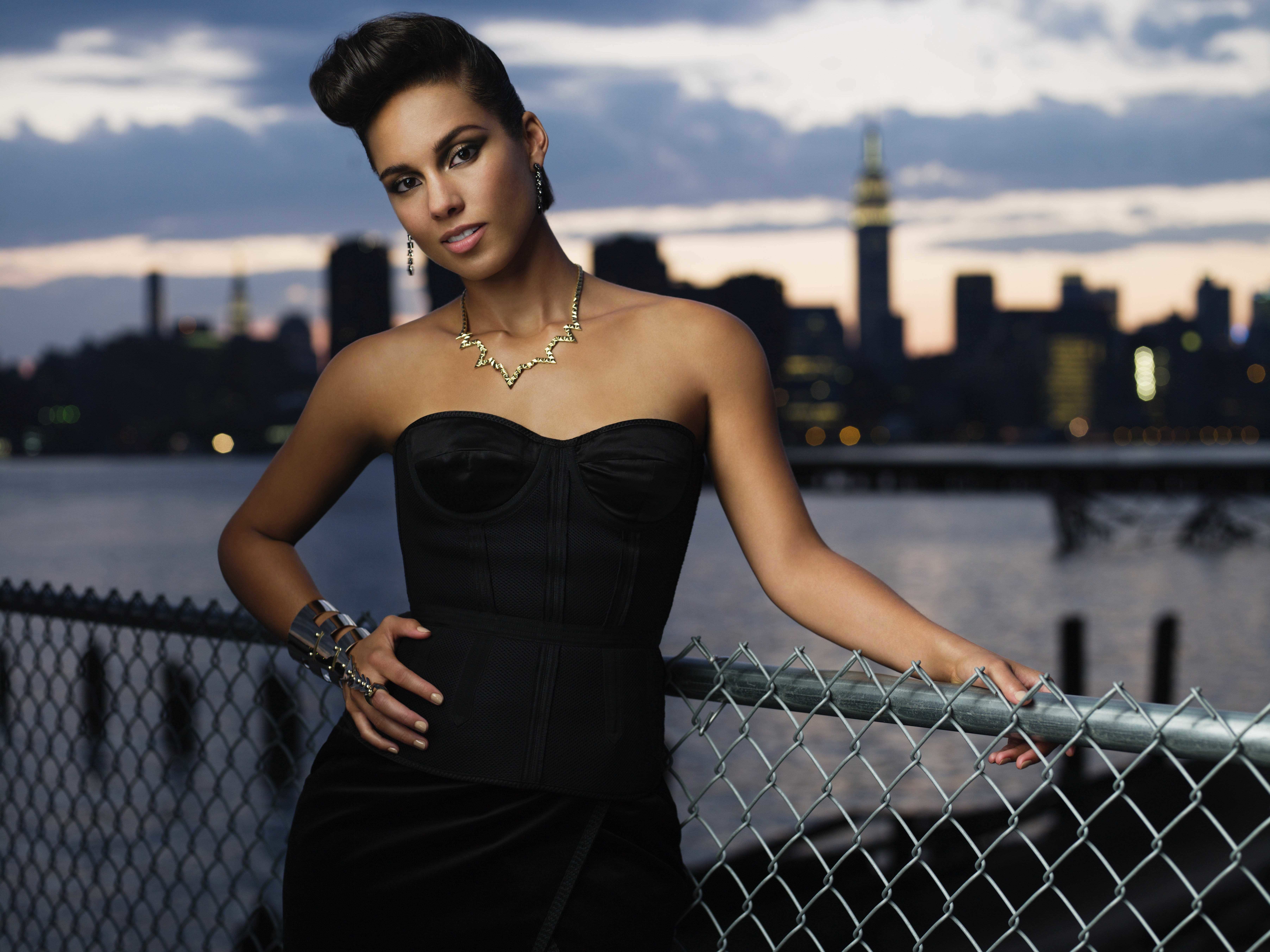 Alicia Keys posing by a fence with New York City skyline HD Wallpaper