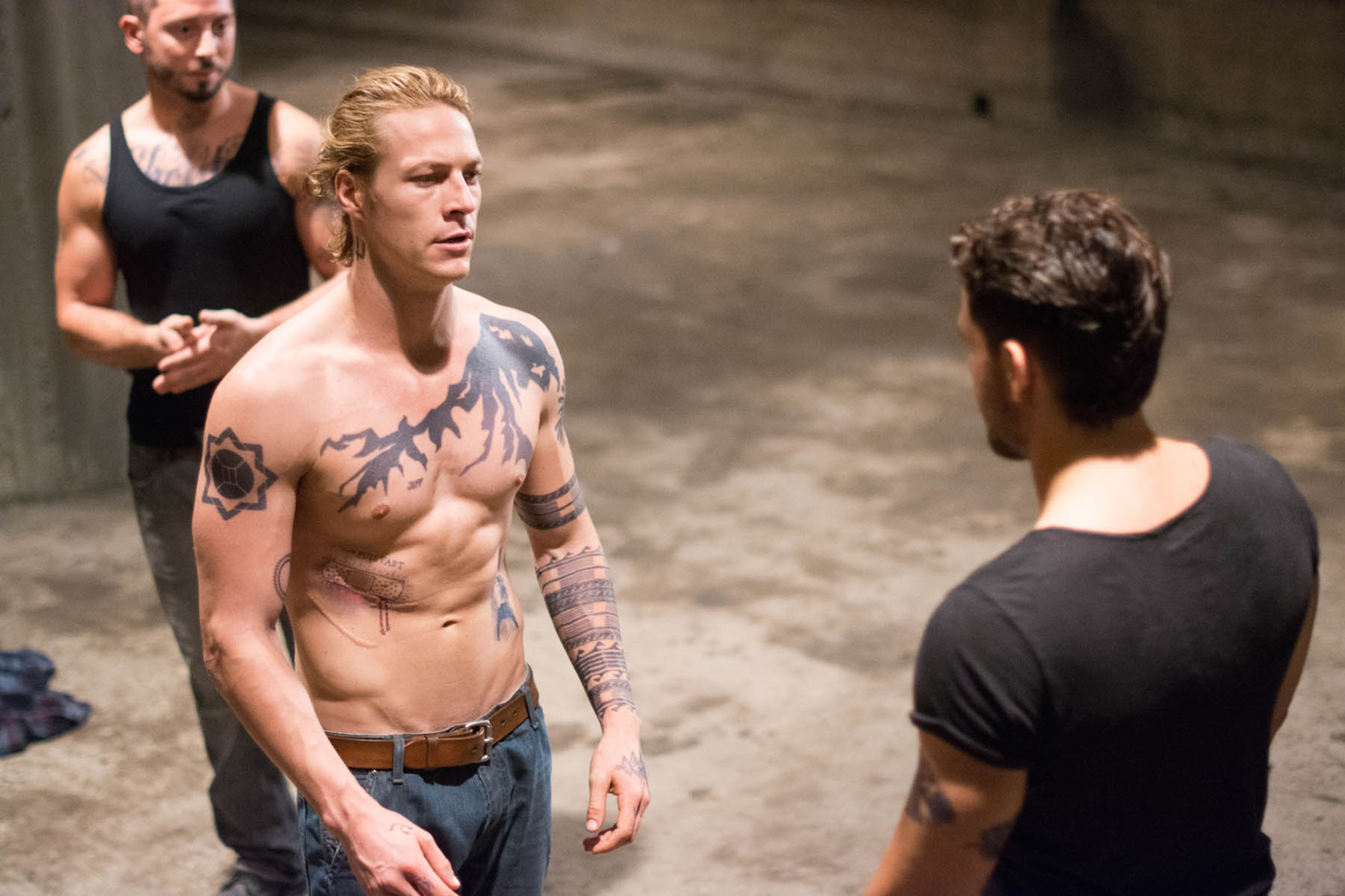 Luke Bracey and two men in a concrete room HD Wallpaper