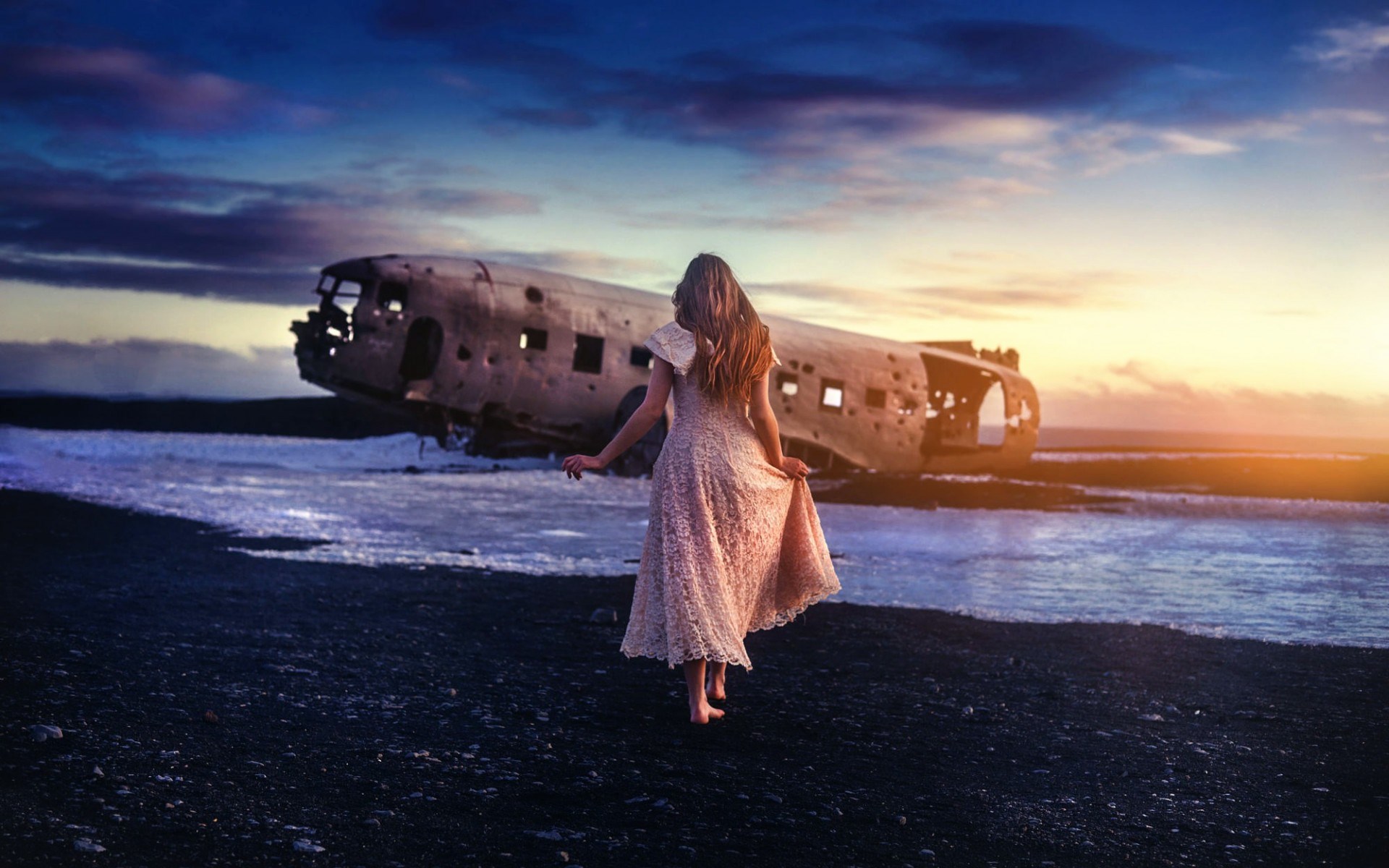 Woman in dress walks towards crashed airplane on beach at sunset HD Wallpaper