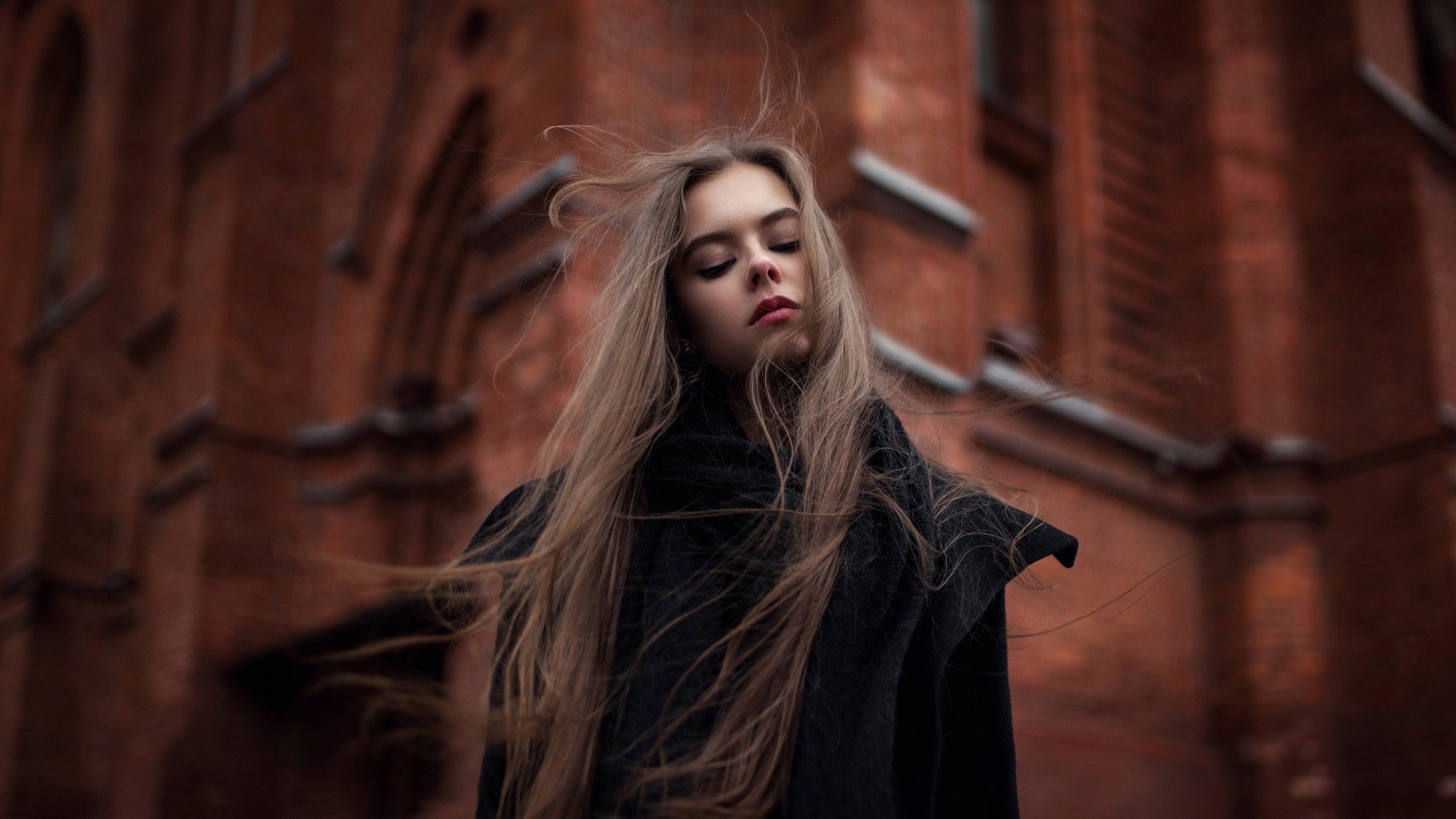 Woman with long hair in front of brick building HD Wallpaper
