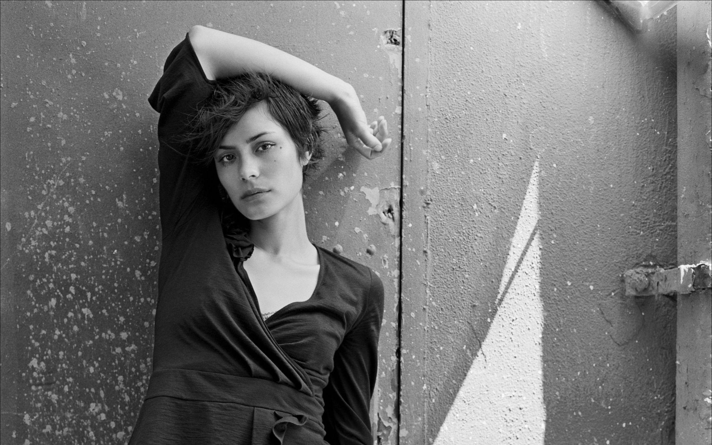 Shannyn Sossamon leaning against a textured wall HD Wallpaper