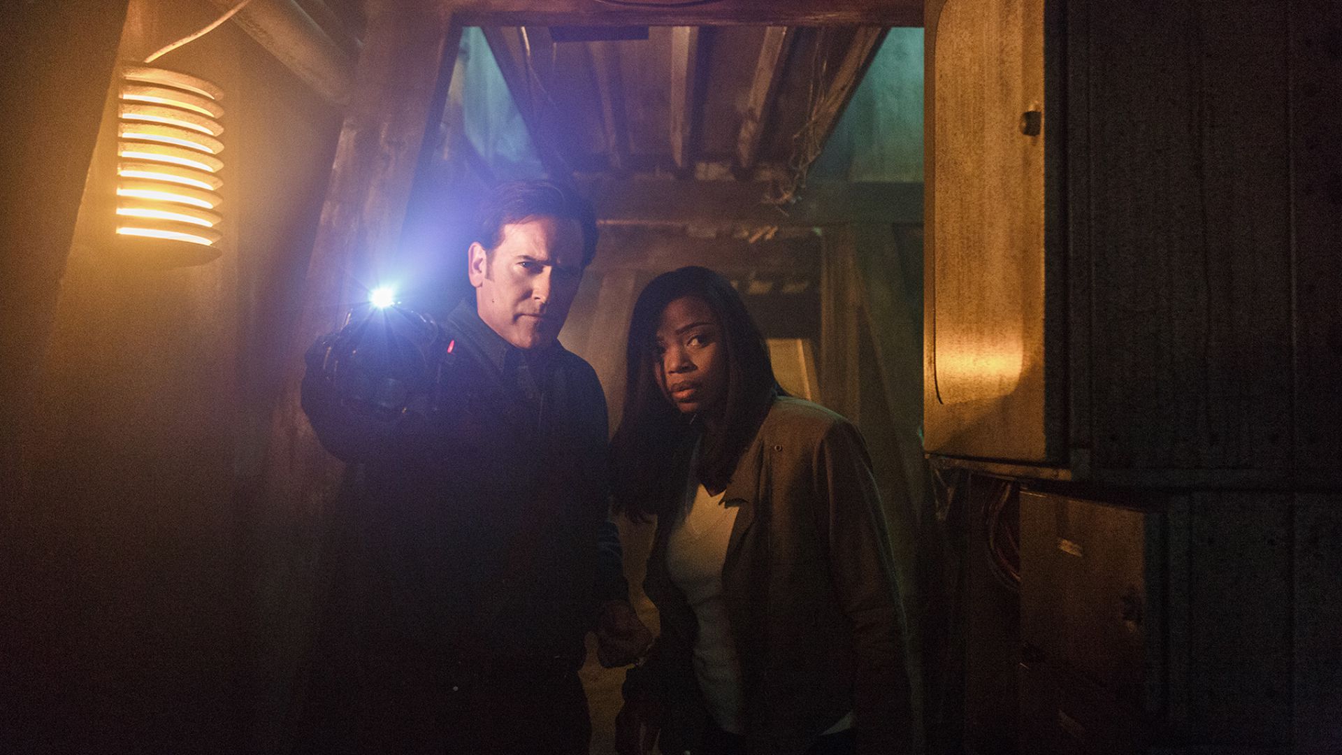 Bruce Campbell and woman in dark corridor HD Wallpaper
