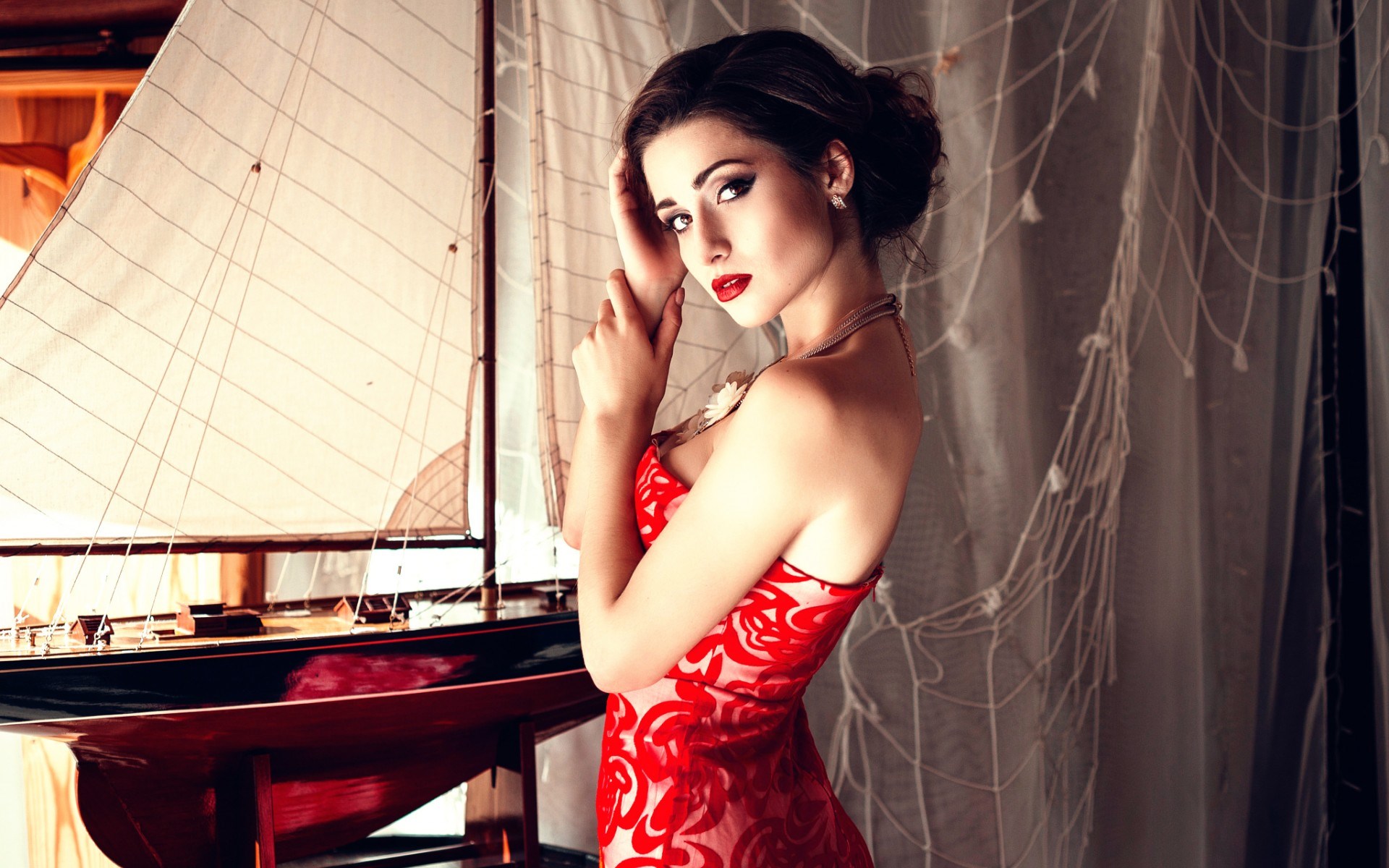 Woman in red dress posing by a model sailboat HD Wallpaper