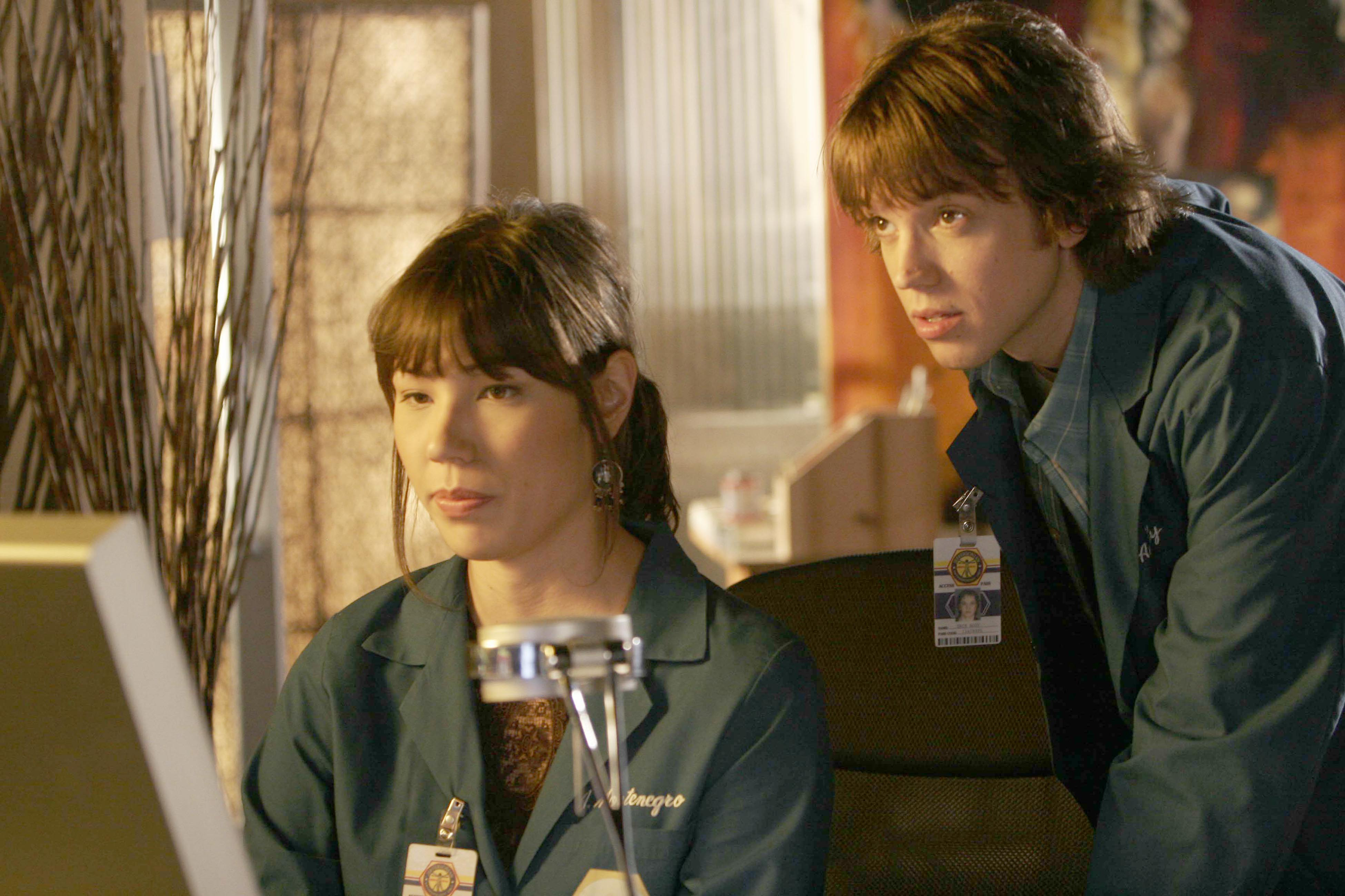 Two people in lab coats looking at a computer HD Wallpaper