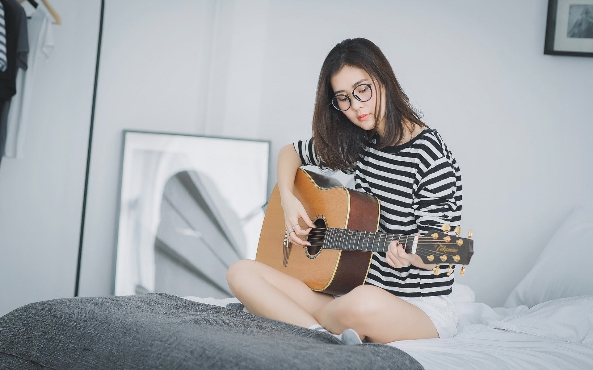 Woman playing guitar on a bed HD Wallpaper