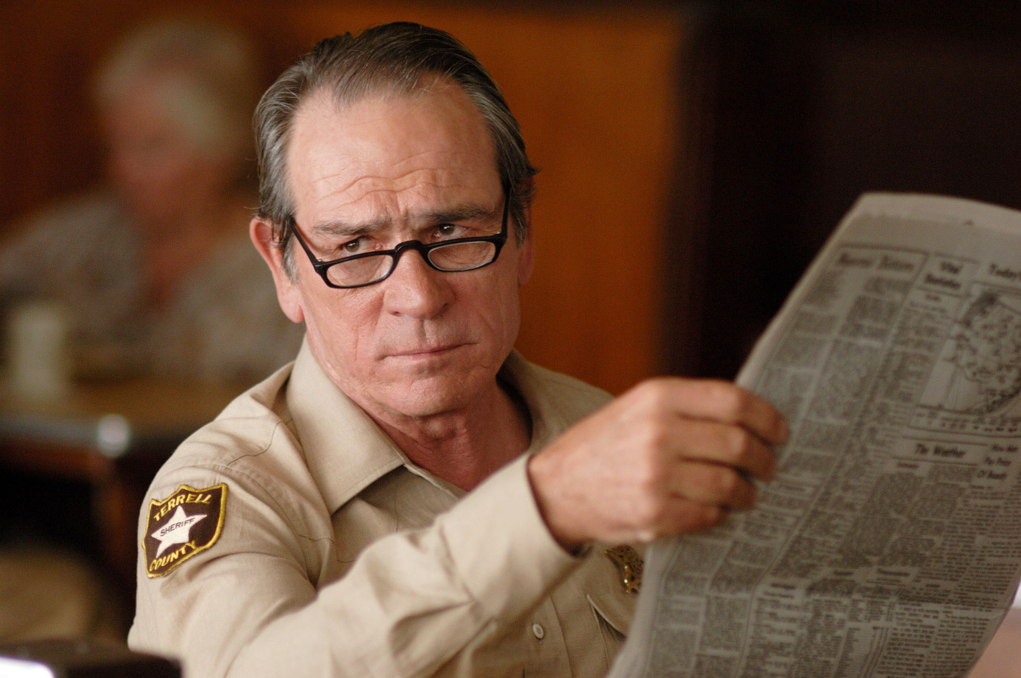 Tommy Lee Jones as Sheriff wearing glasses and reading newspaper HD Wallpaper