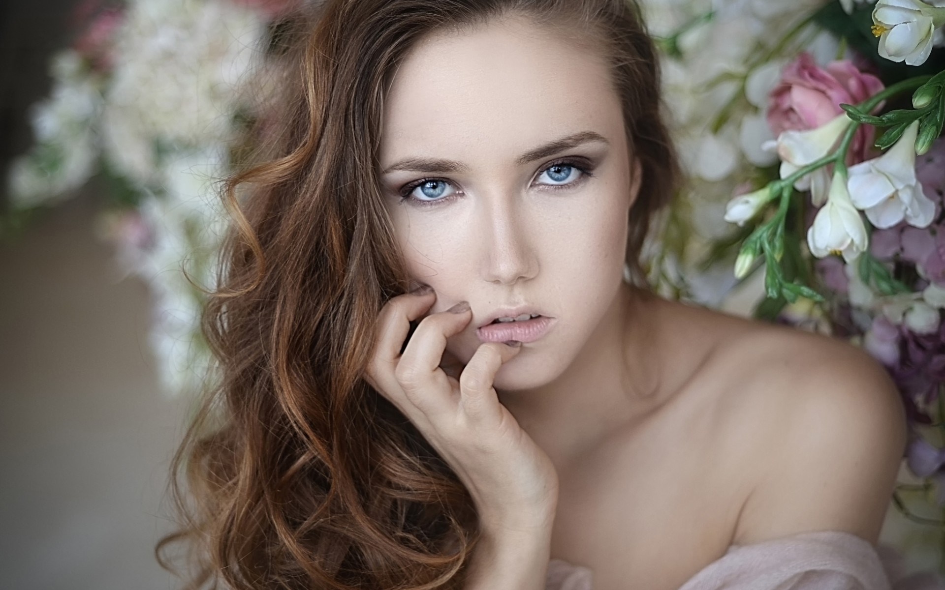 Woman with blue eyes and brown hair among flowers HD Wallpaper