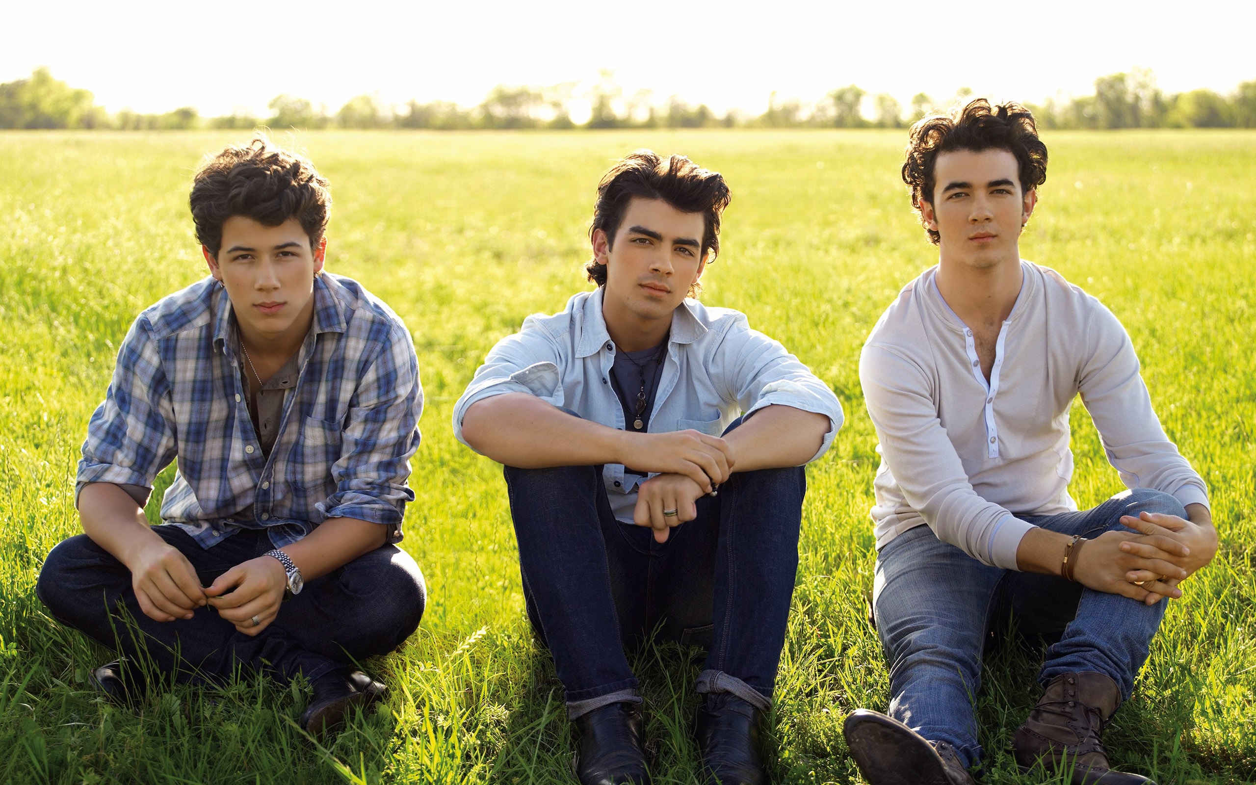 Nick Jonas and two other men sitting in a field HD Wallpaper
