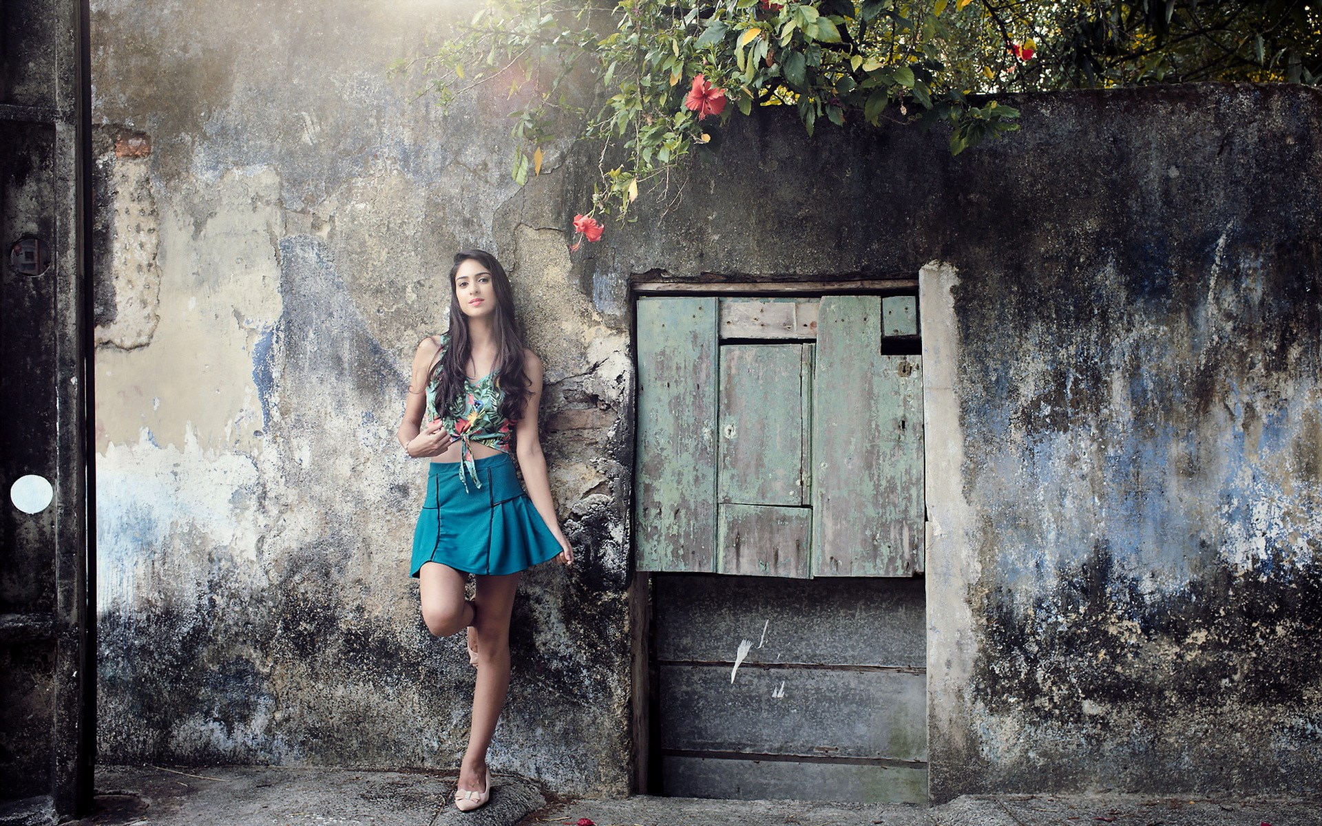 Woman leaning against a weathered wall with a wooden door HD Wallpaper