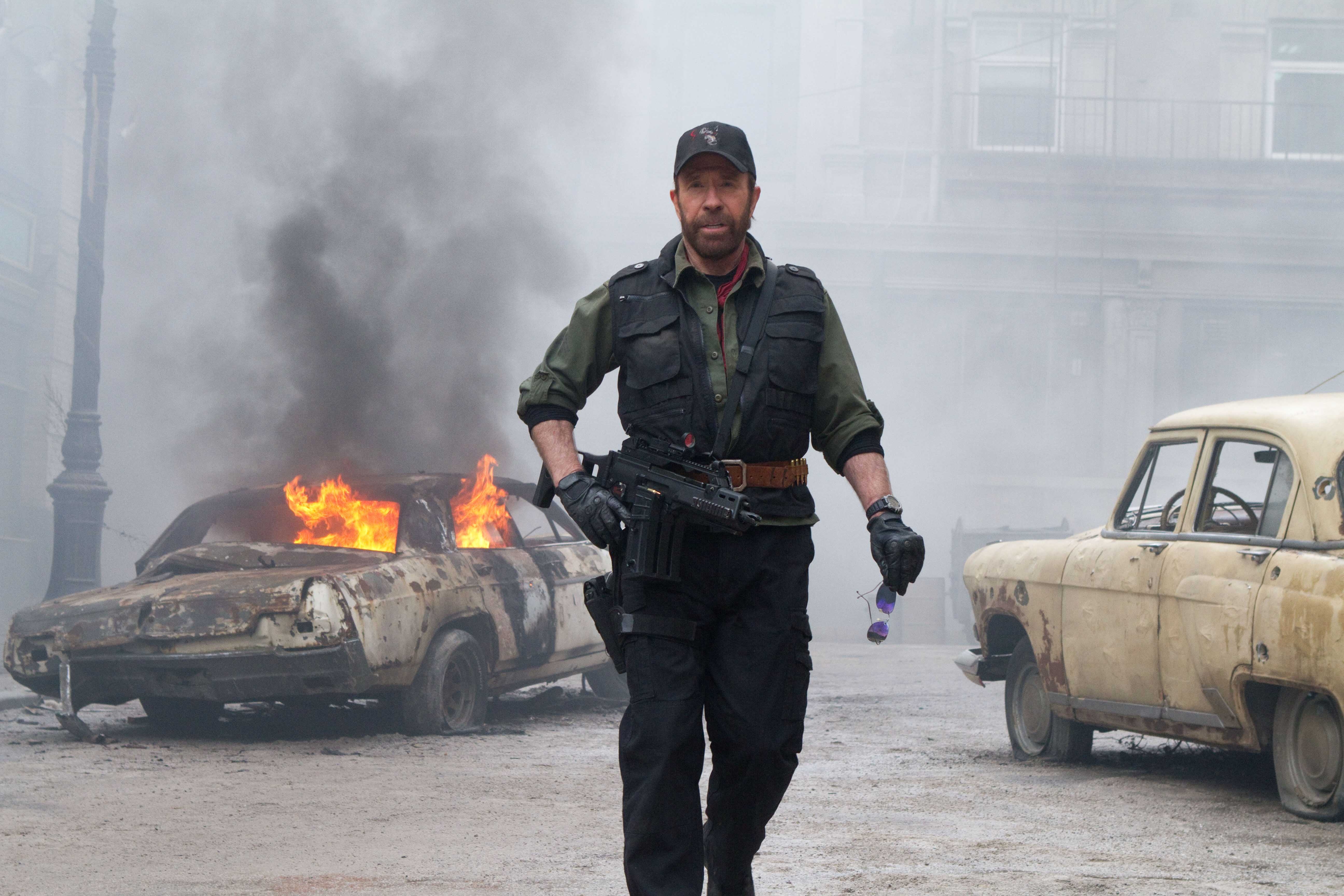 Chuck Norris in a scene with burning cars HD Wallpaper