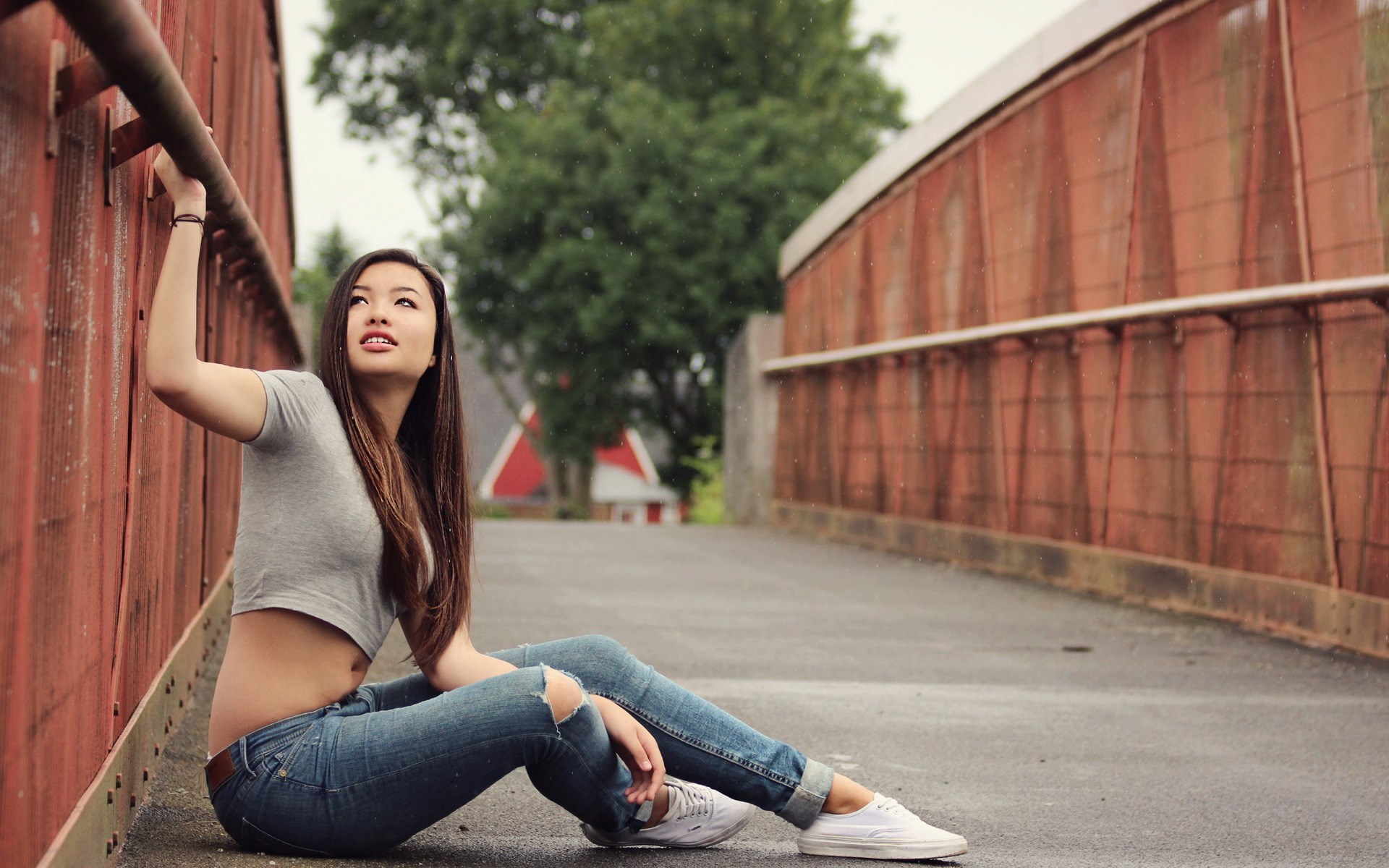 Woman in ripped jeans and crop top sitting on a bridge HD Wallpaper