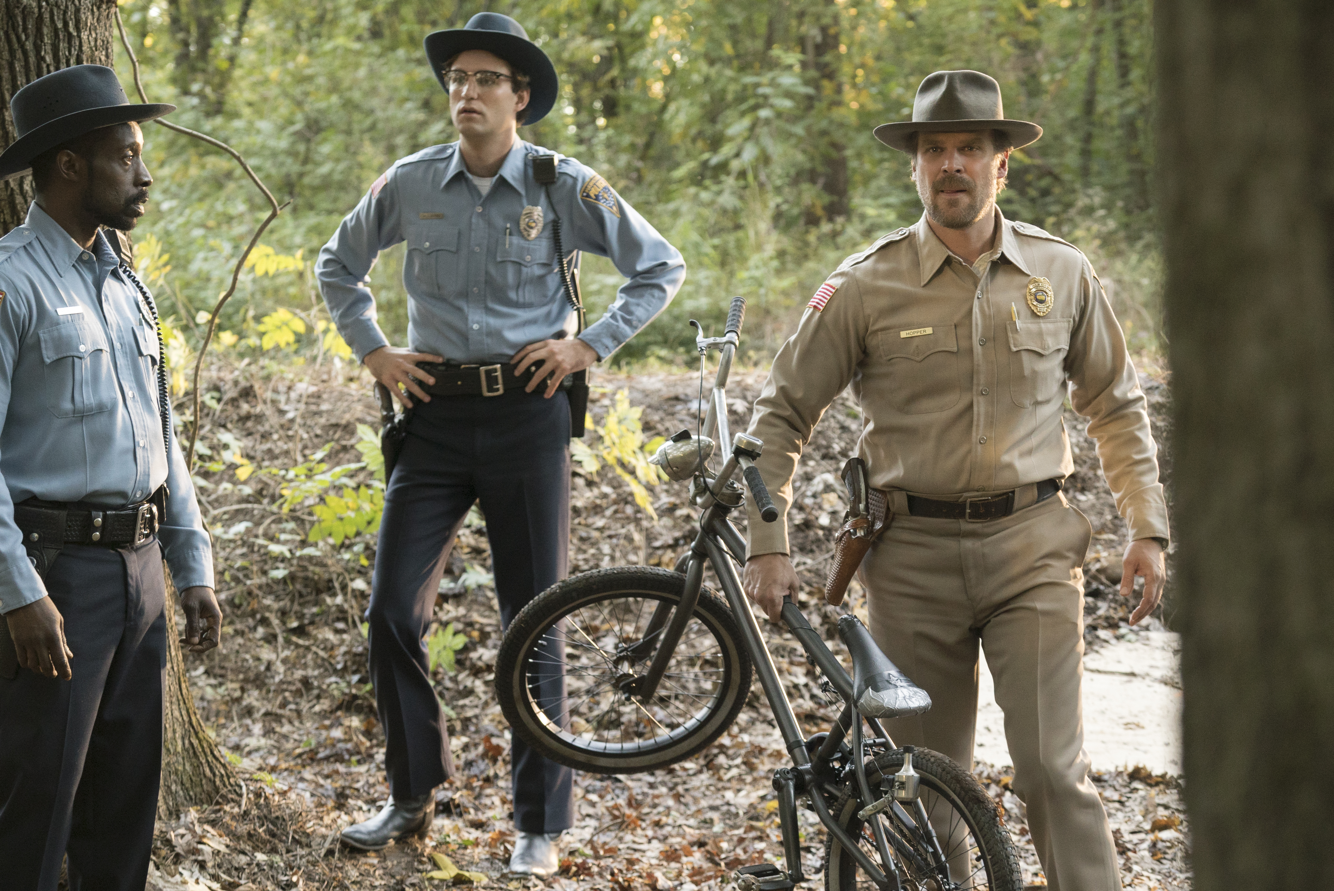 David Harbour and two police officers in a forest HD Wallpaper