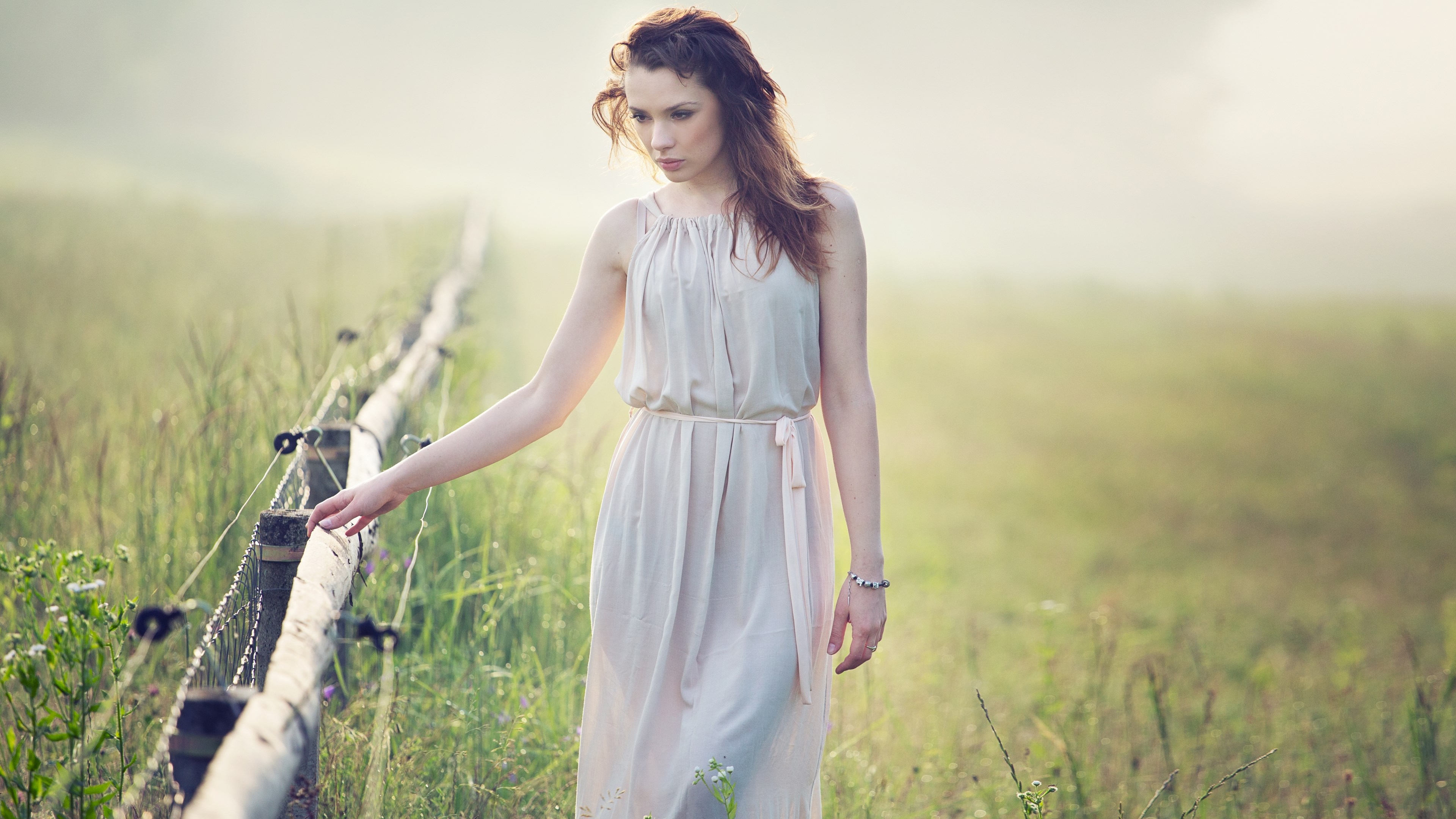 Woman in a light dress walking by a fence HD Wallpaper