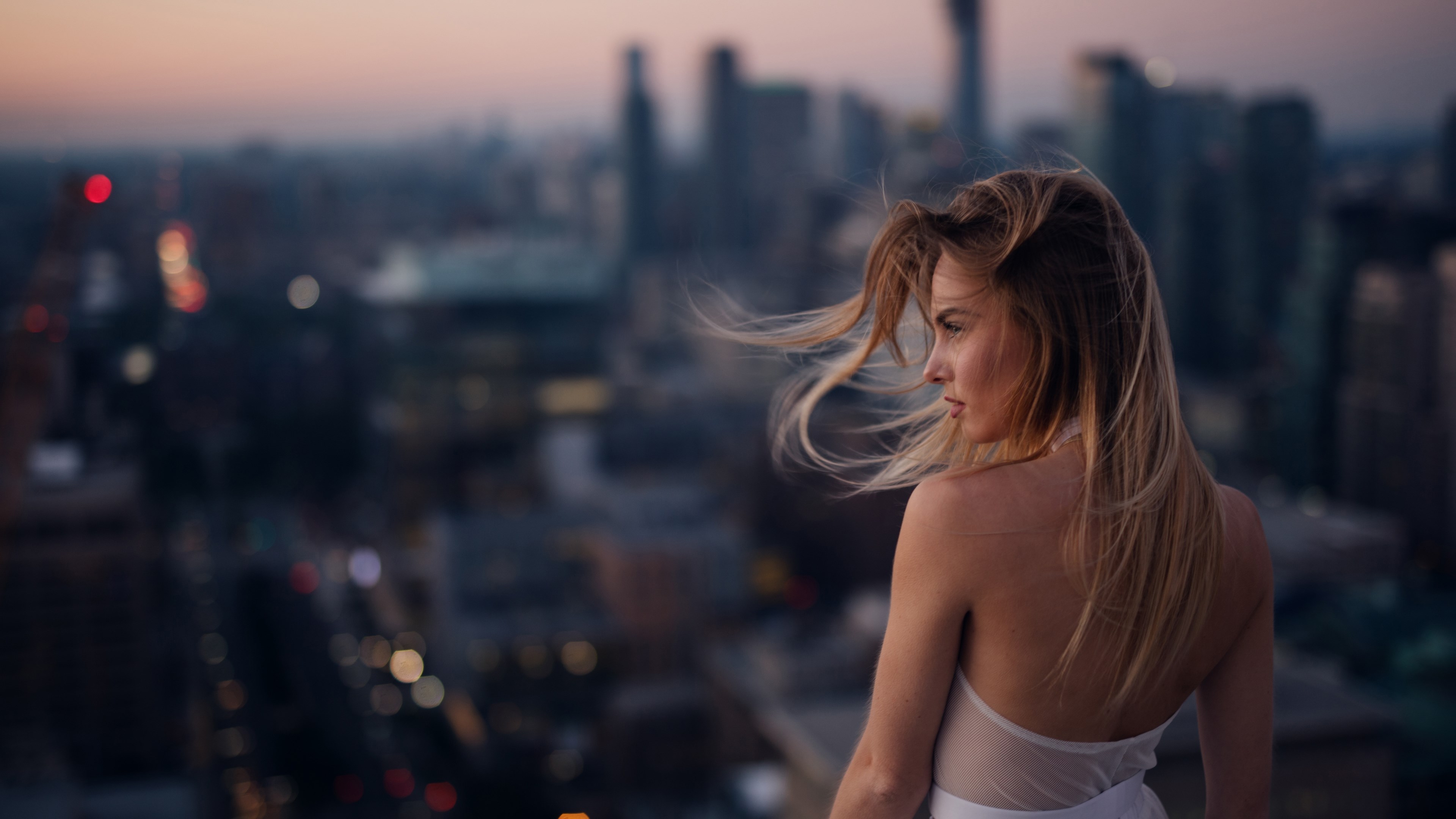 Woman on a rooftop overlooking city at dusk HD Wallpaper