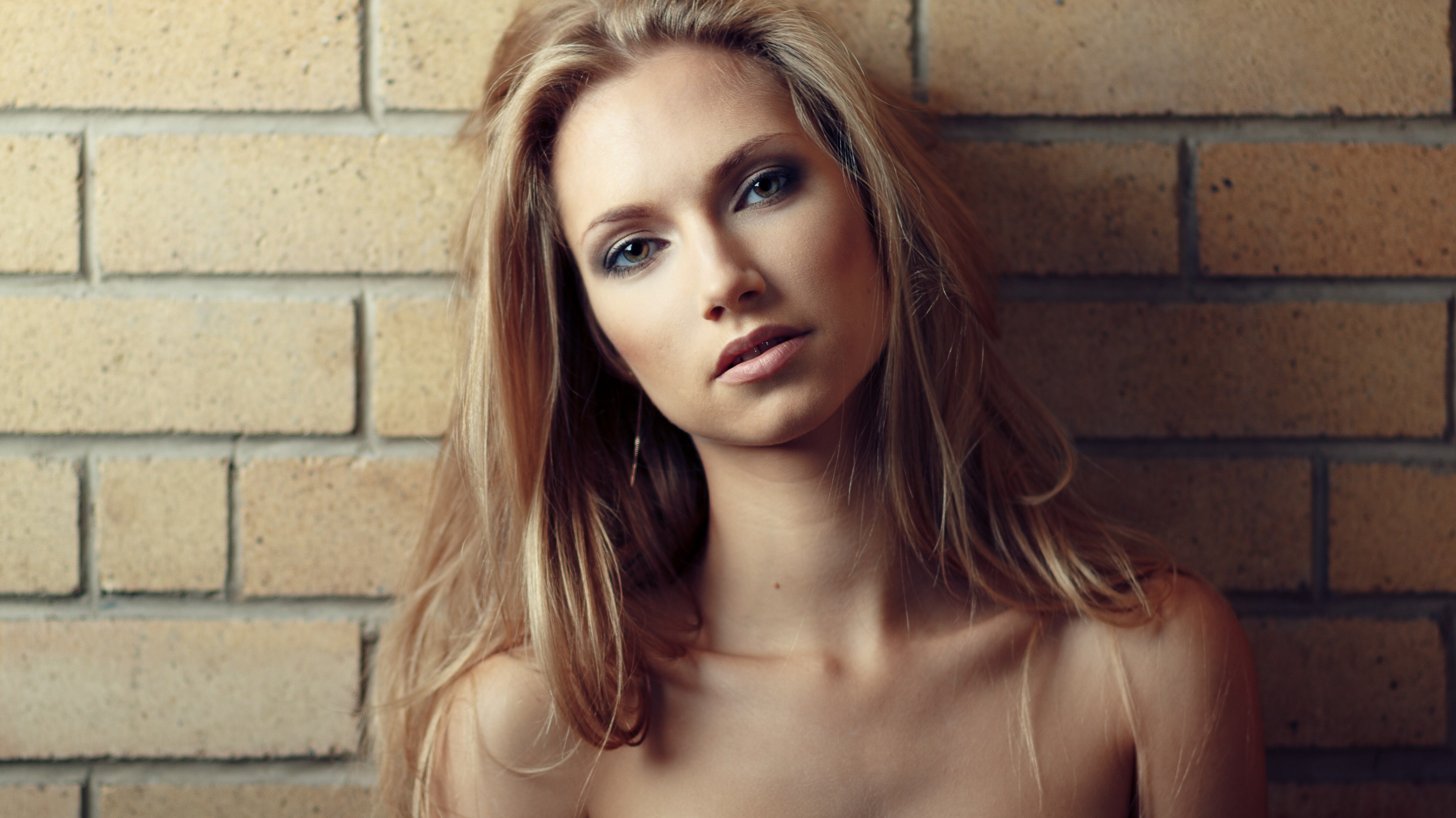 Woman leaning against a brick wall HD Wallpaper