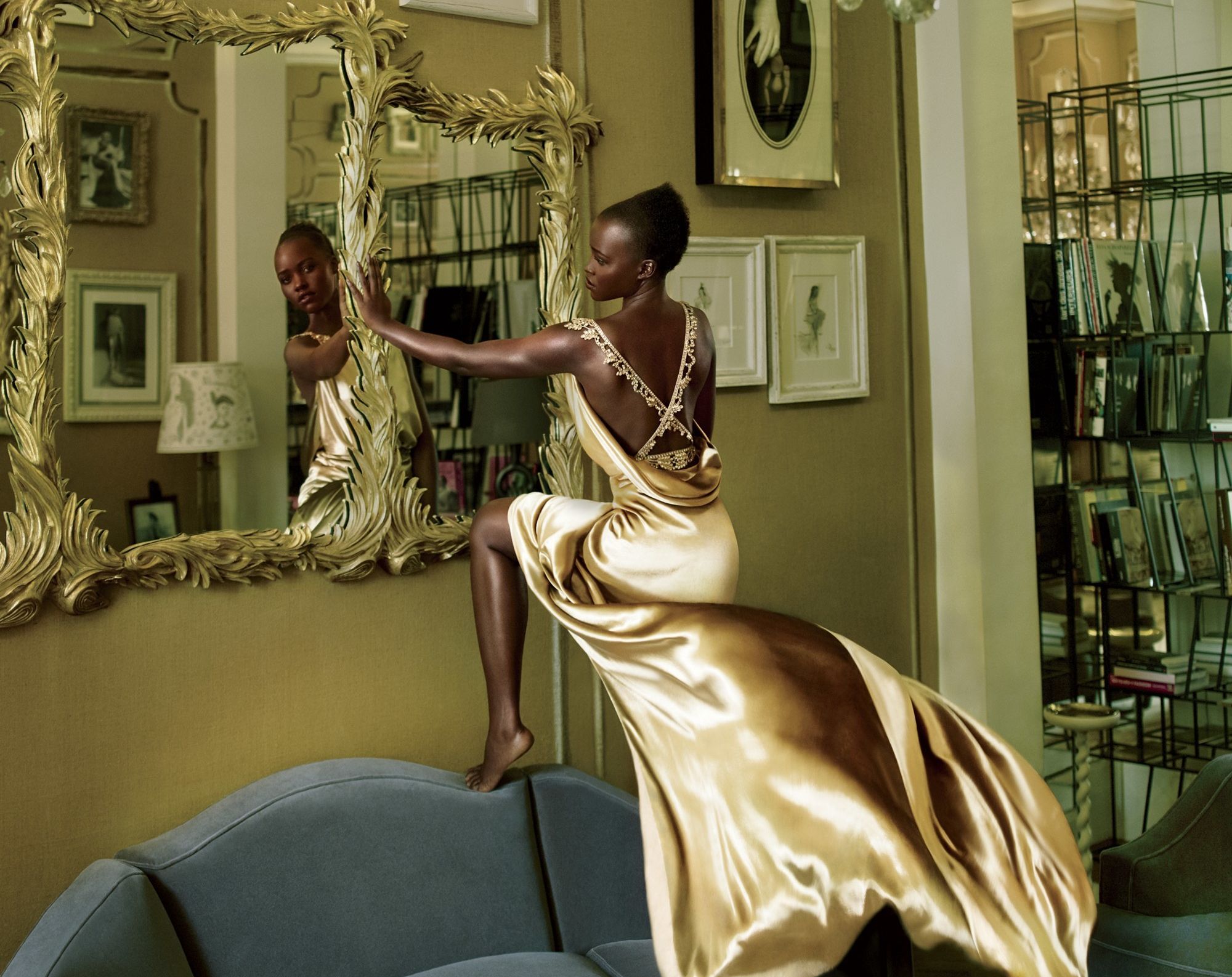 Lupita Nyong'o in a golden dress by a mirror HD Wallpaper