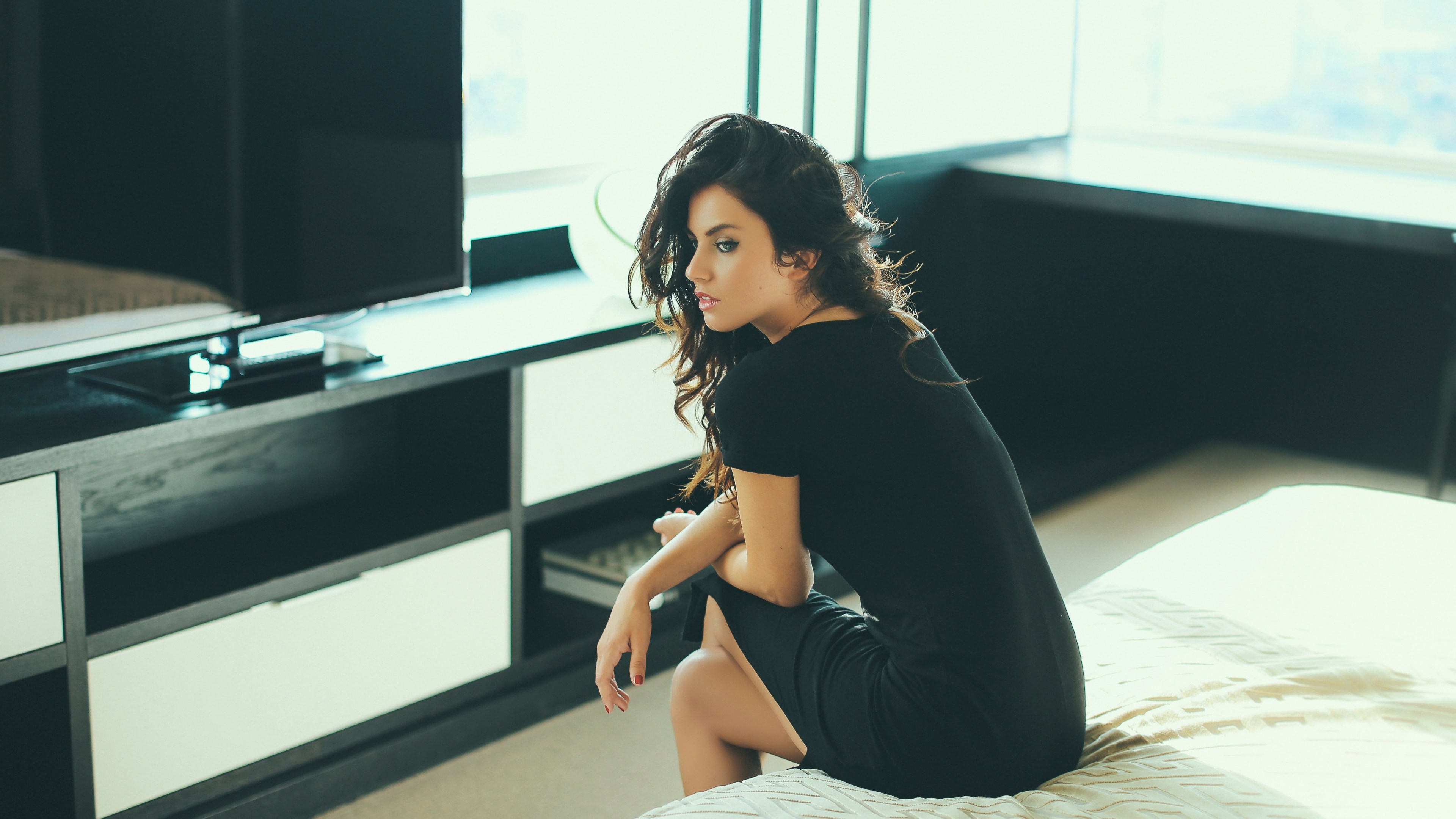 Woman in black dress sitting on a bed HD Wallpaper