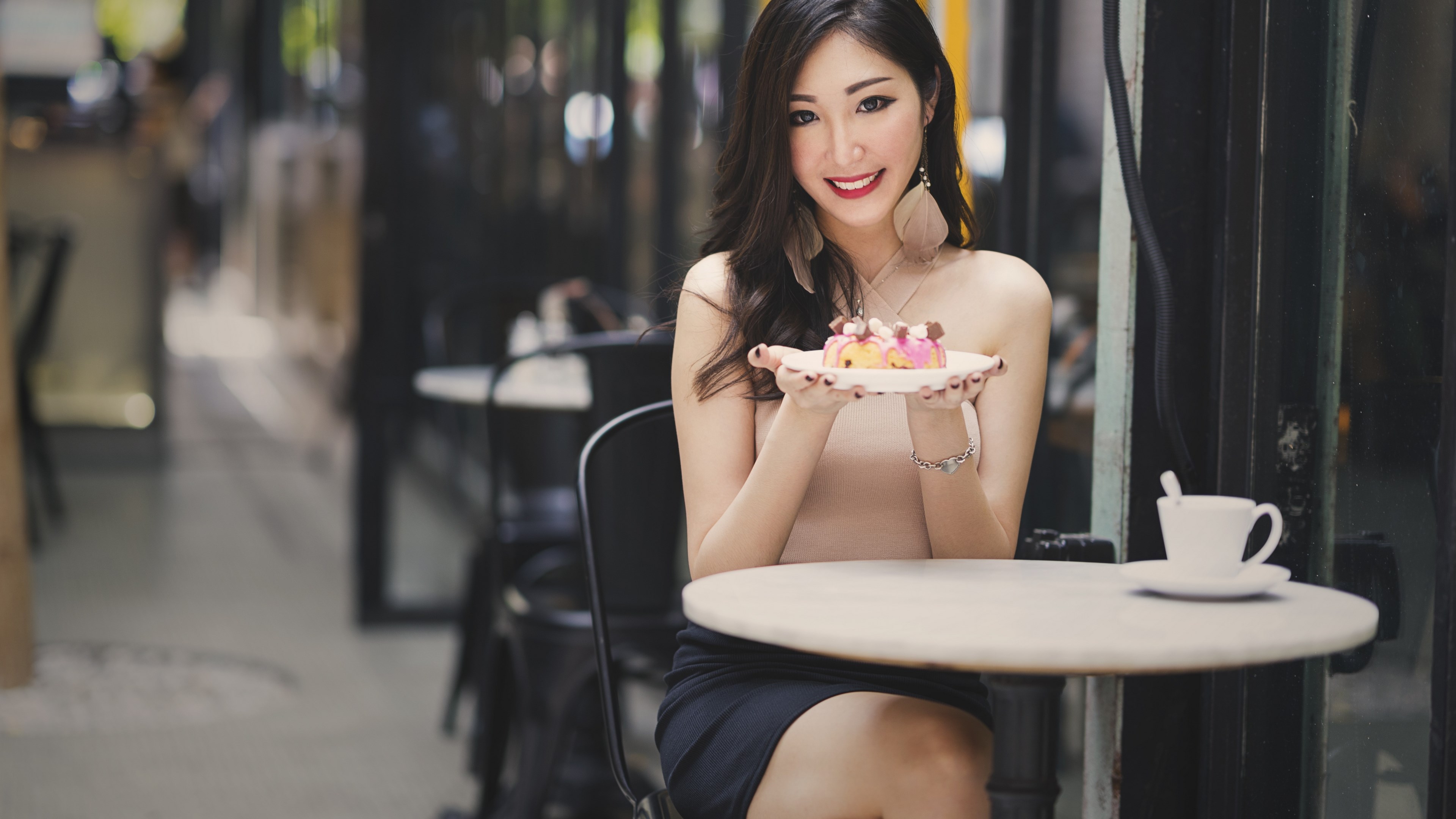 Woman holding a dessert at a cafe table HD Wallpaper