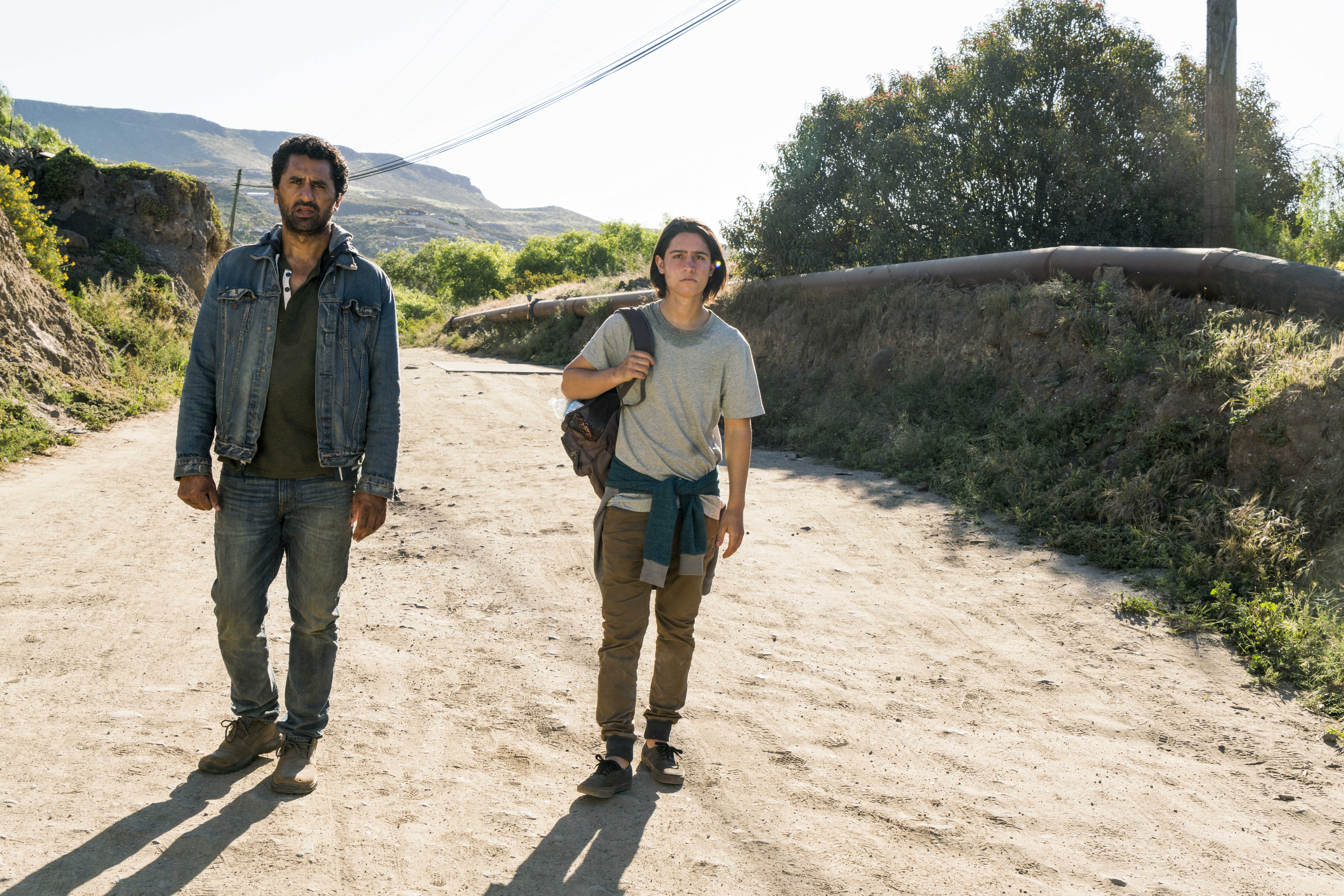 Cliff Curtis and a young person walking on a dirt road HD Wallpaper
