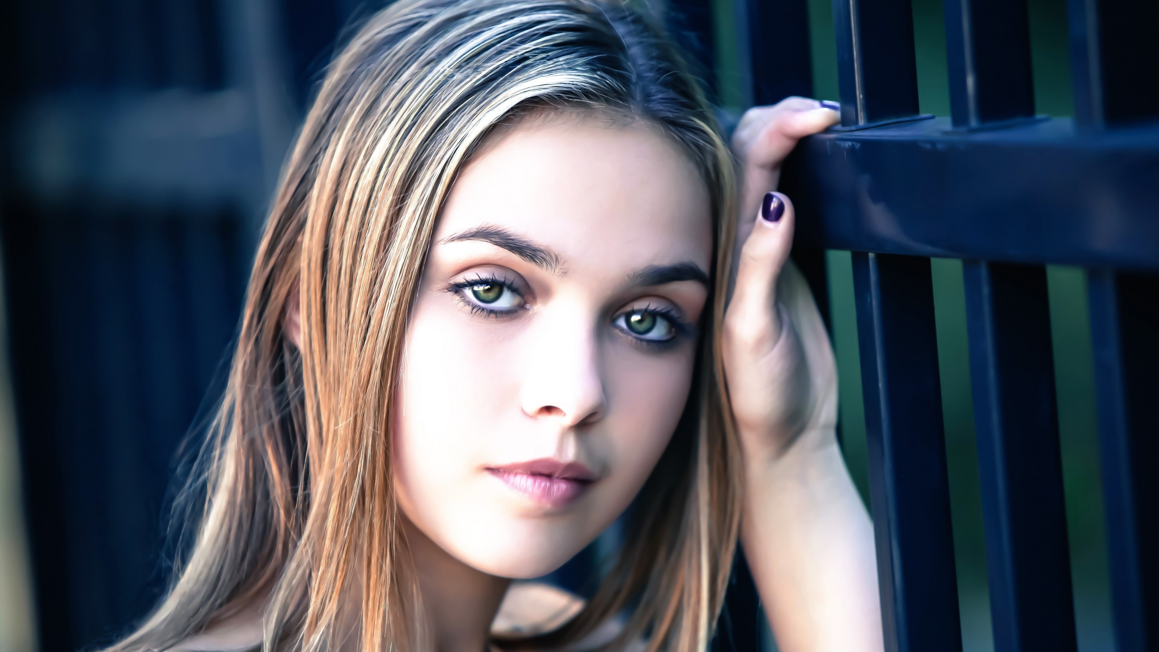 Young woman with green eyes leaning on a fence HD Wallpaper
