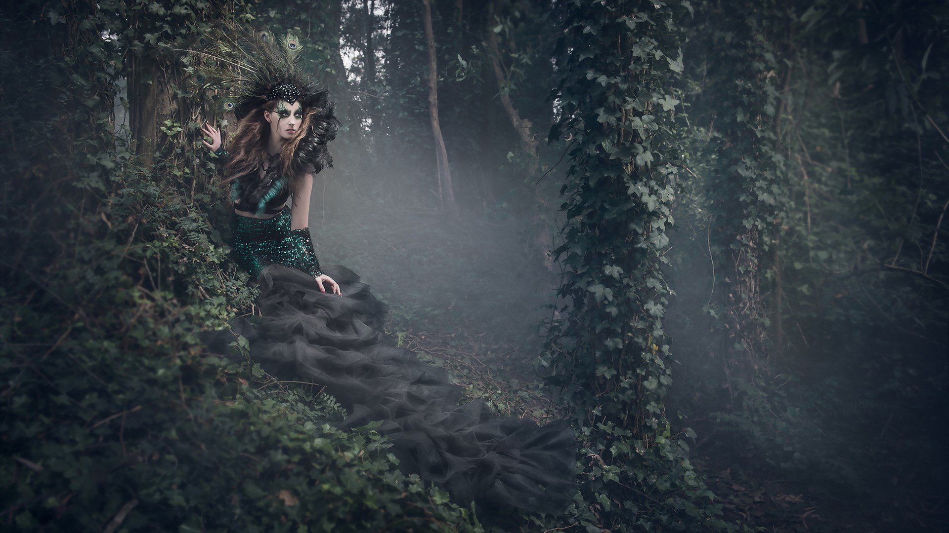 Woman in peacock-themed costume in a misty forest HD Wallpaper