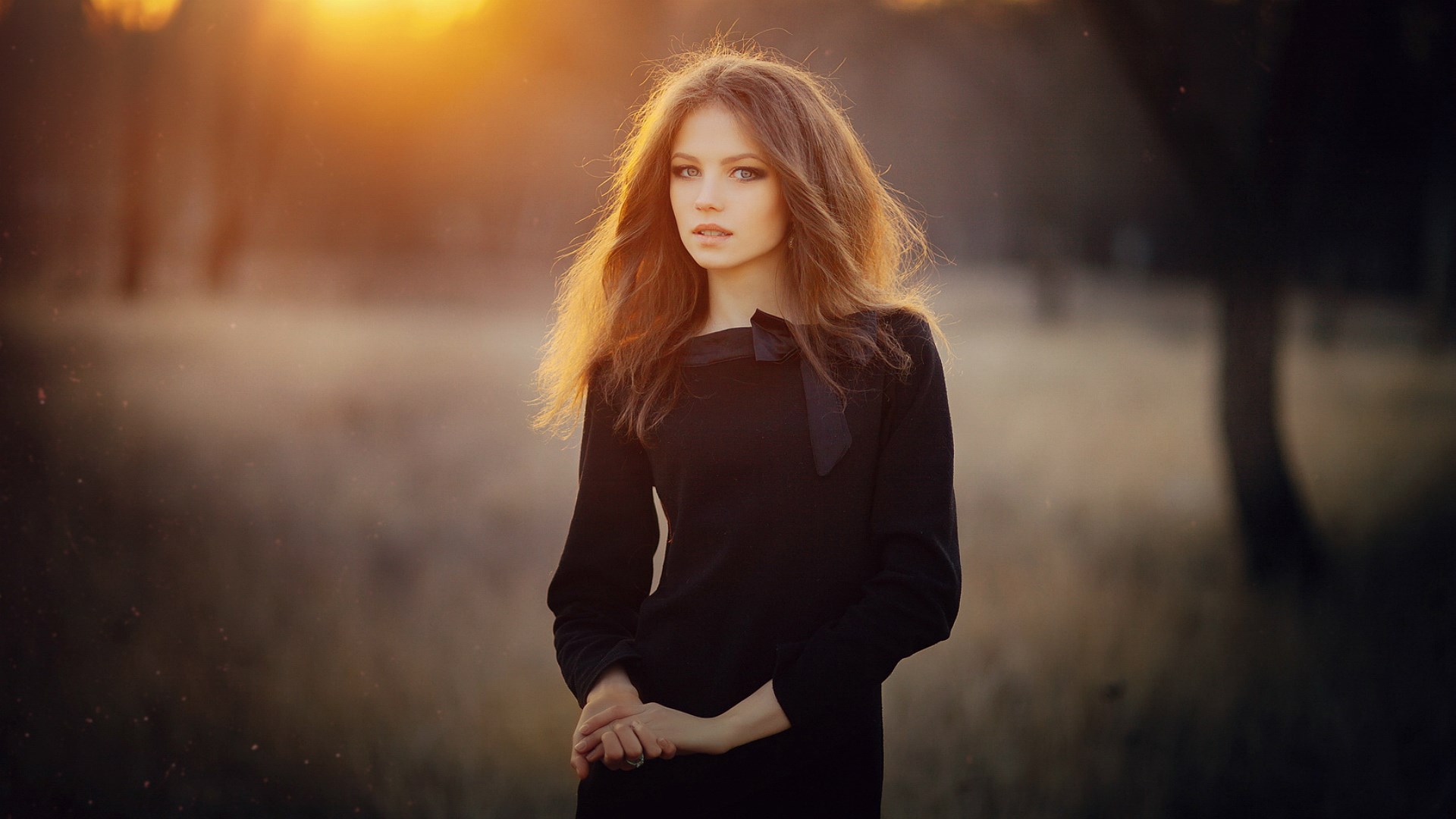 Woman in black dress in a field at sunset HD Wallpaper