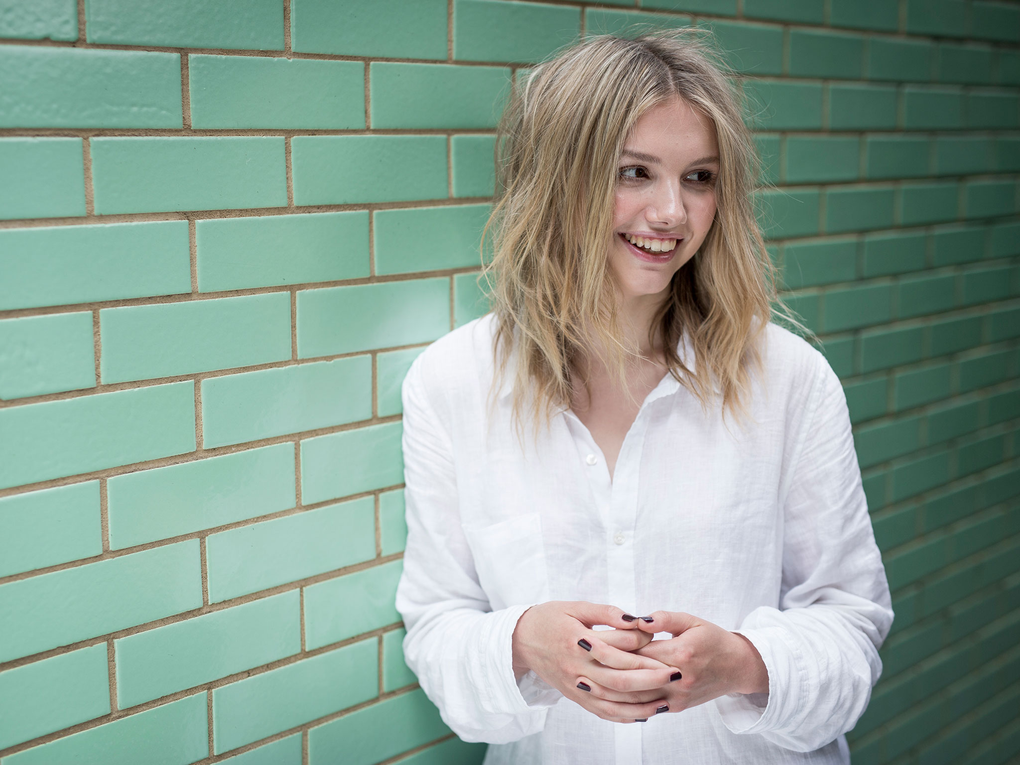 Hannah Murray against a green brick wall HD Wallpaper
