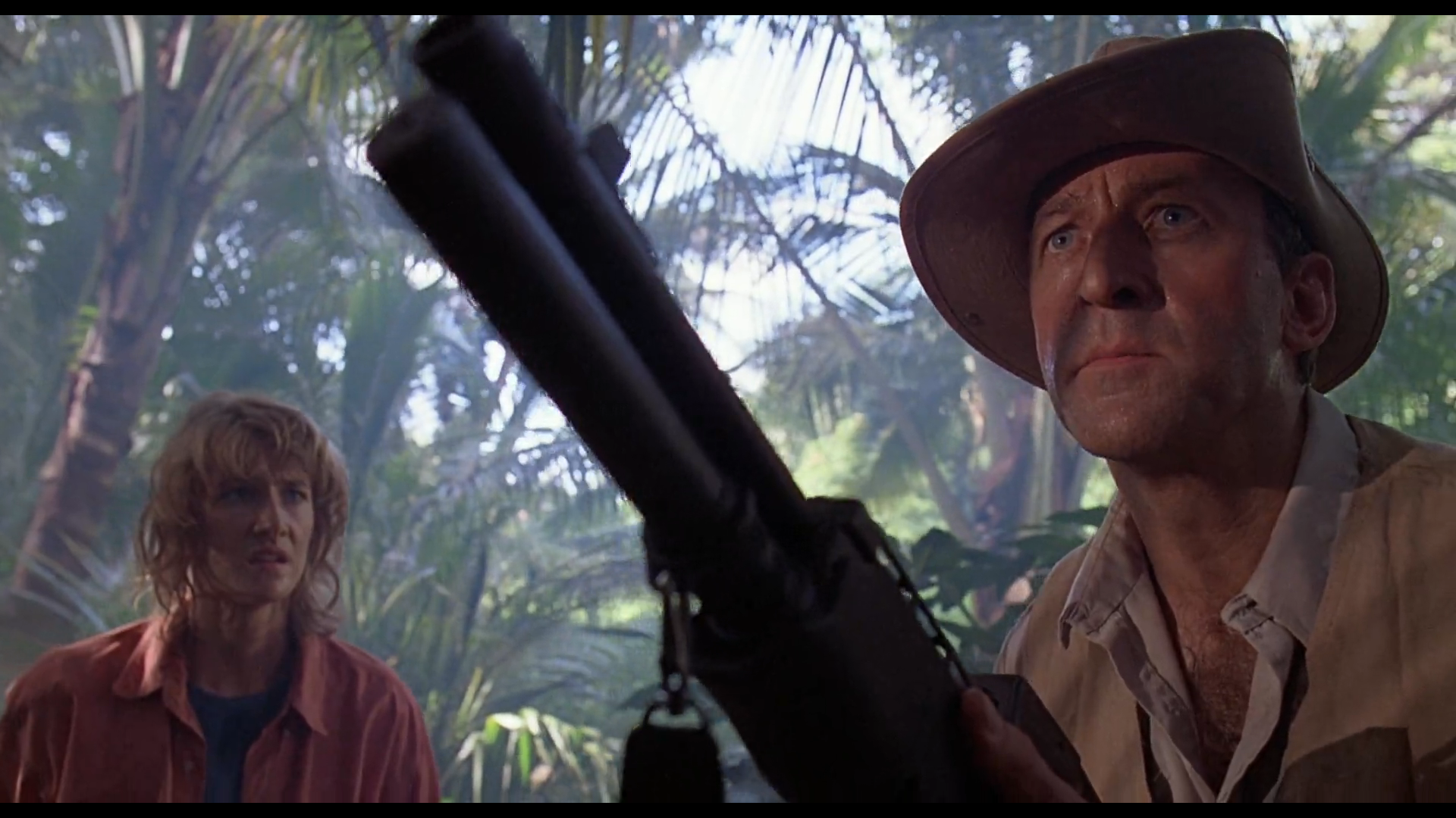 Man with shotgun and woman in jungle HD Wallpaper