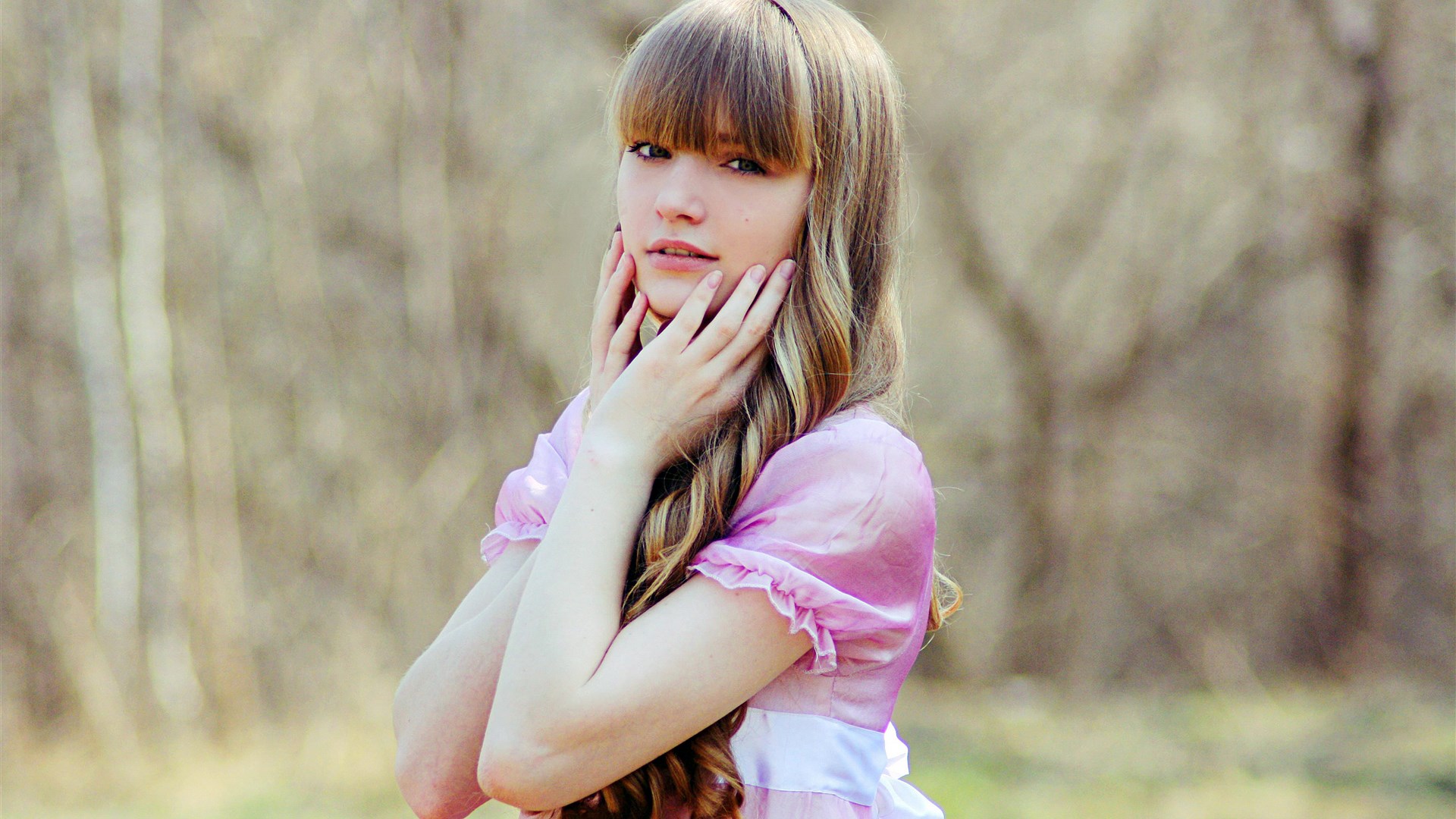 Young woman in pink dress with hands on face HD Wallpaper