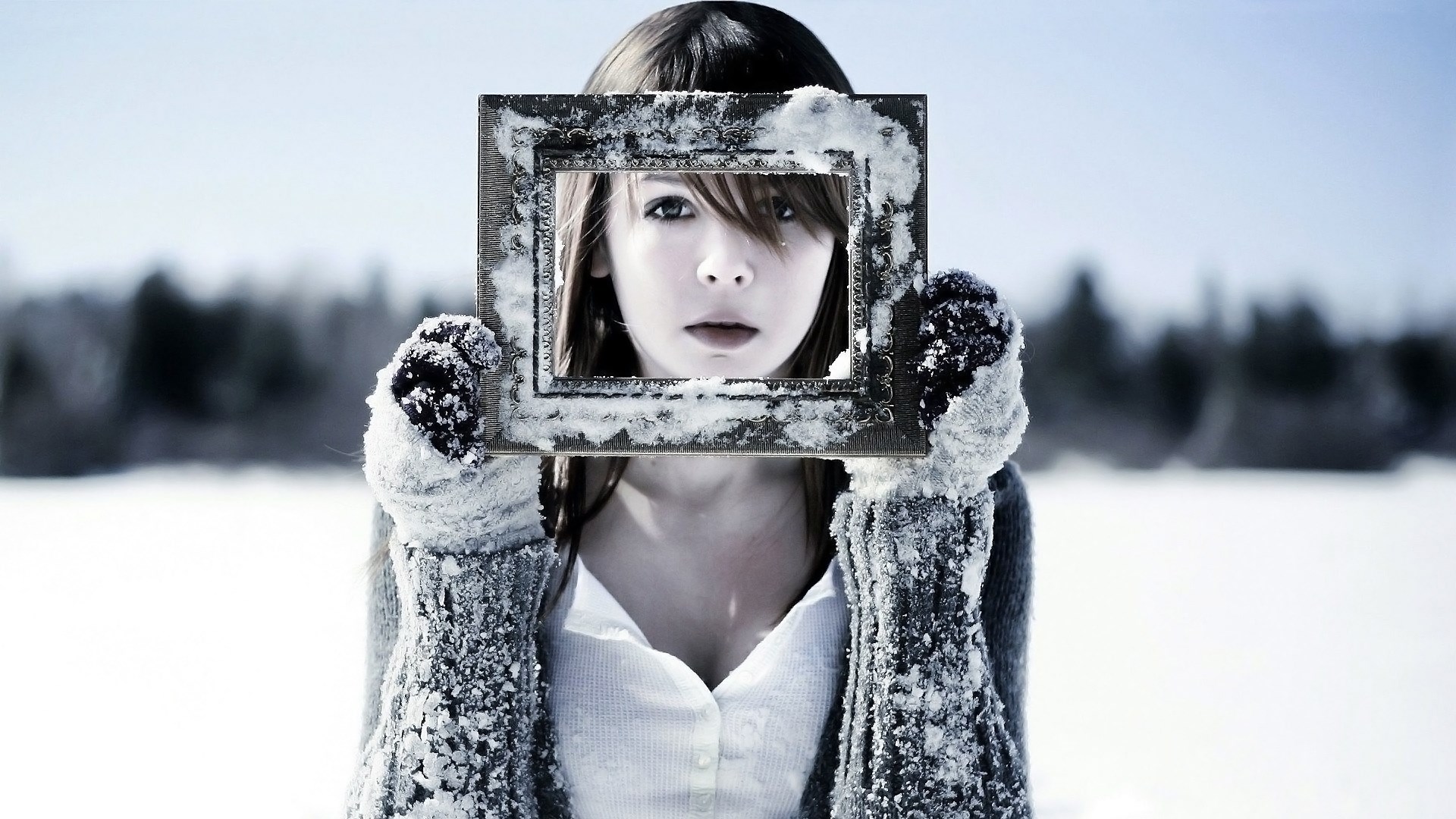 Girl holding a snow-covered frame in a winter landscape HD Wallpaper