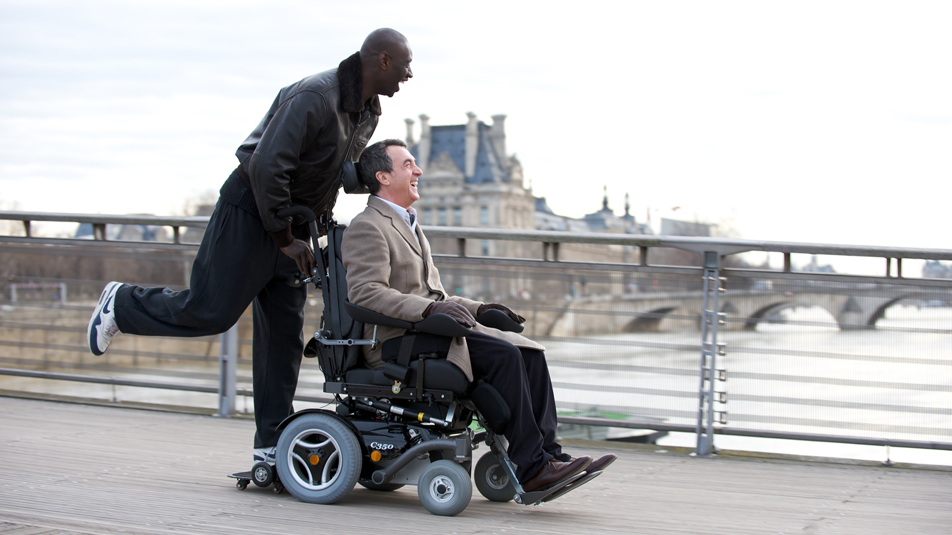 Omar Sy in a wheelchair on a bridge in Paris HD Wallpaper