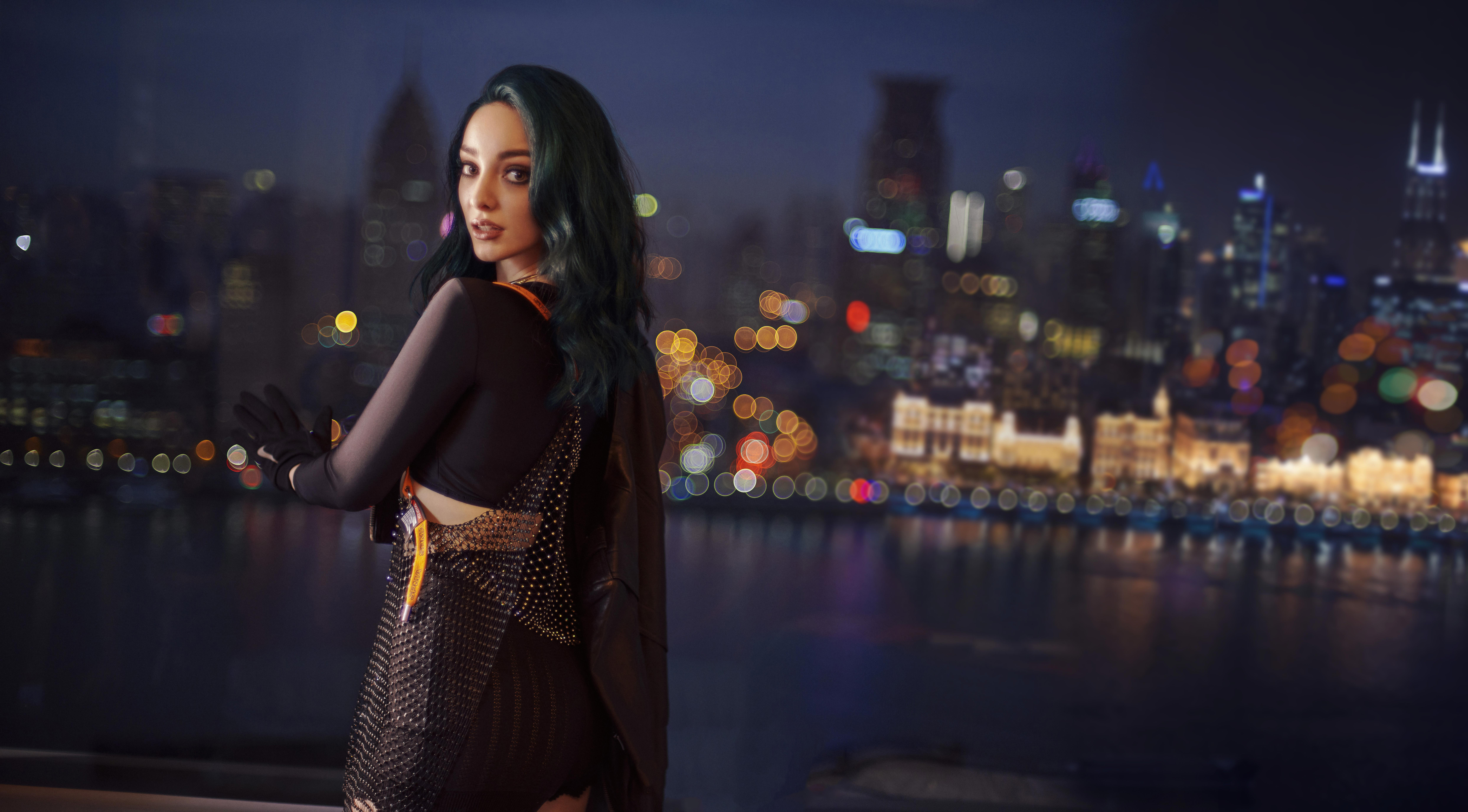 Emma Dumont posing in front of a city skyline at night HD Wallpaper