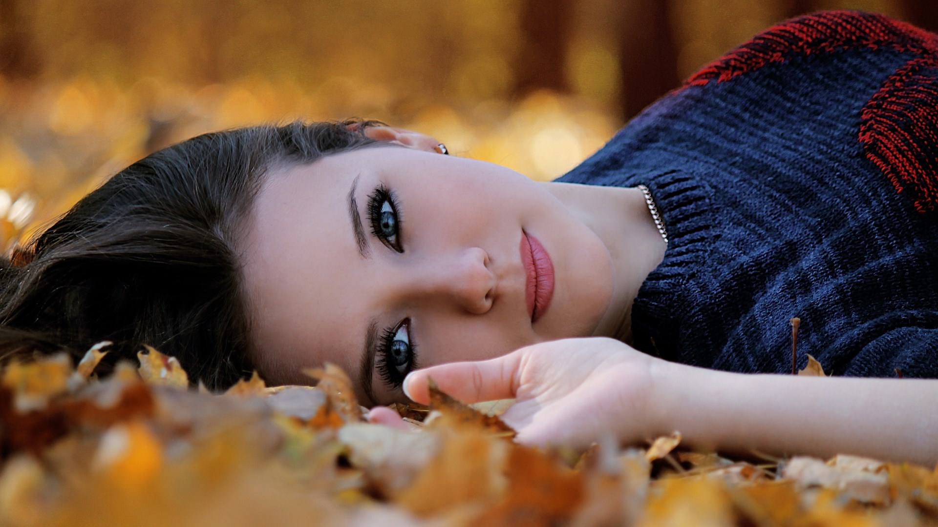 Woman lying in autumn leaves HD Wallpaper