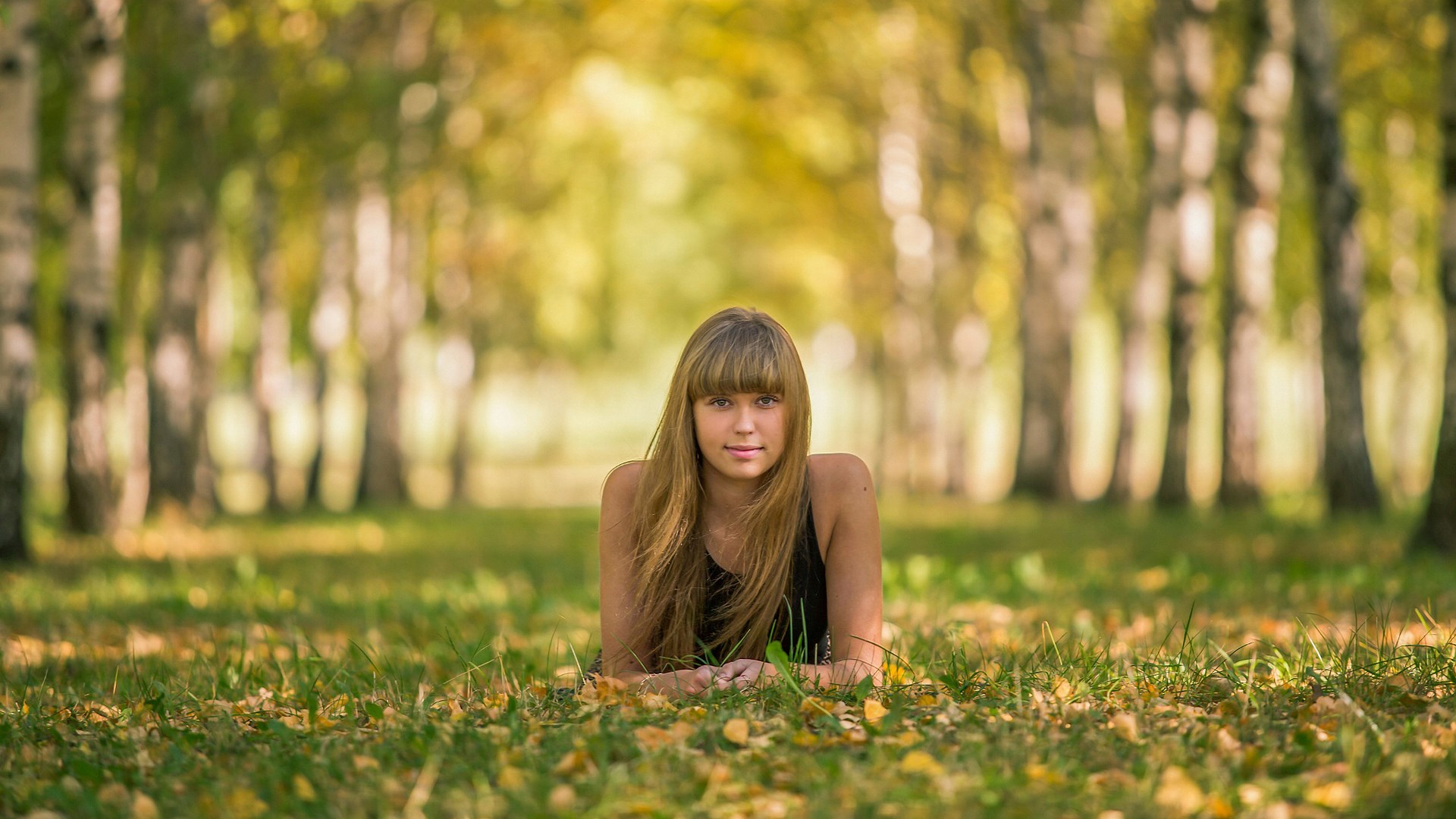 Young woman lying in grass in a park HD Wallpaper