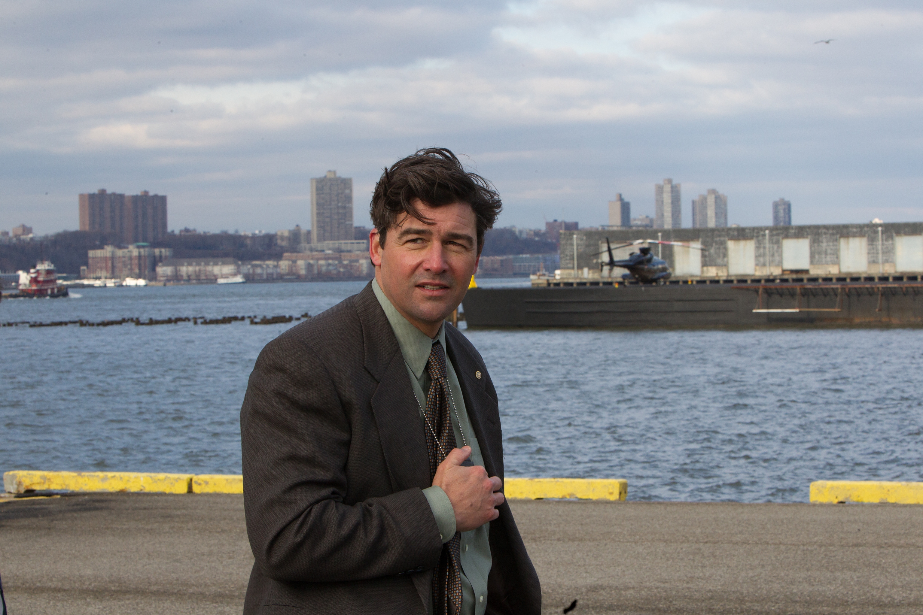 Kyle Chandler on a pier with a helicopter and city in background HD Wallpaper