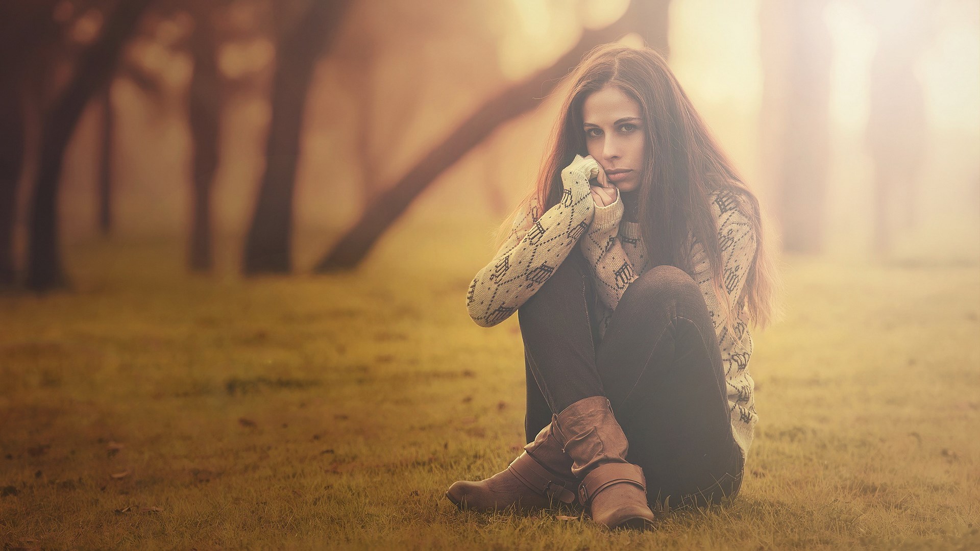 A young woman sits alone in a foggy forest HD Wallpaper