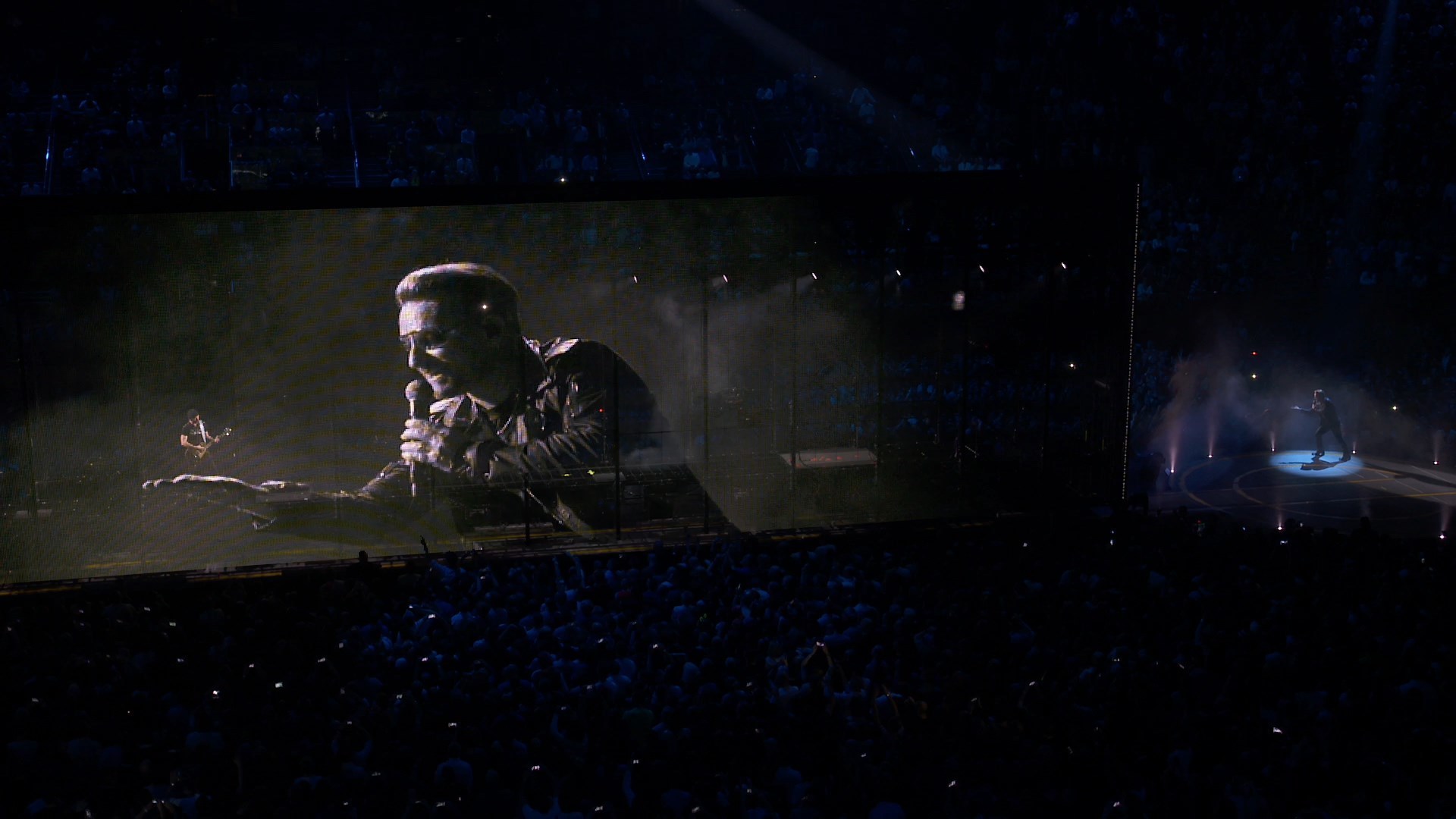Bono performing on stage with large screen display HD Wallpaper