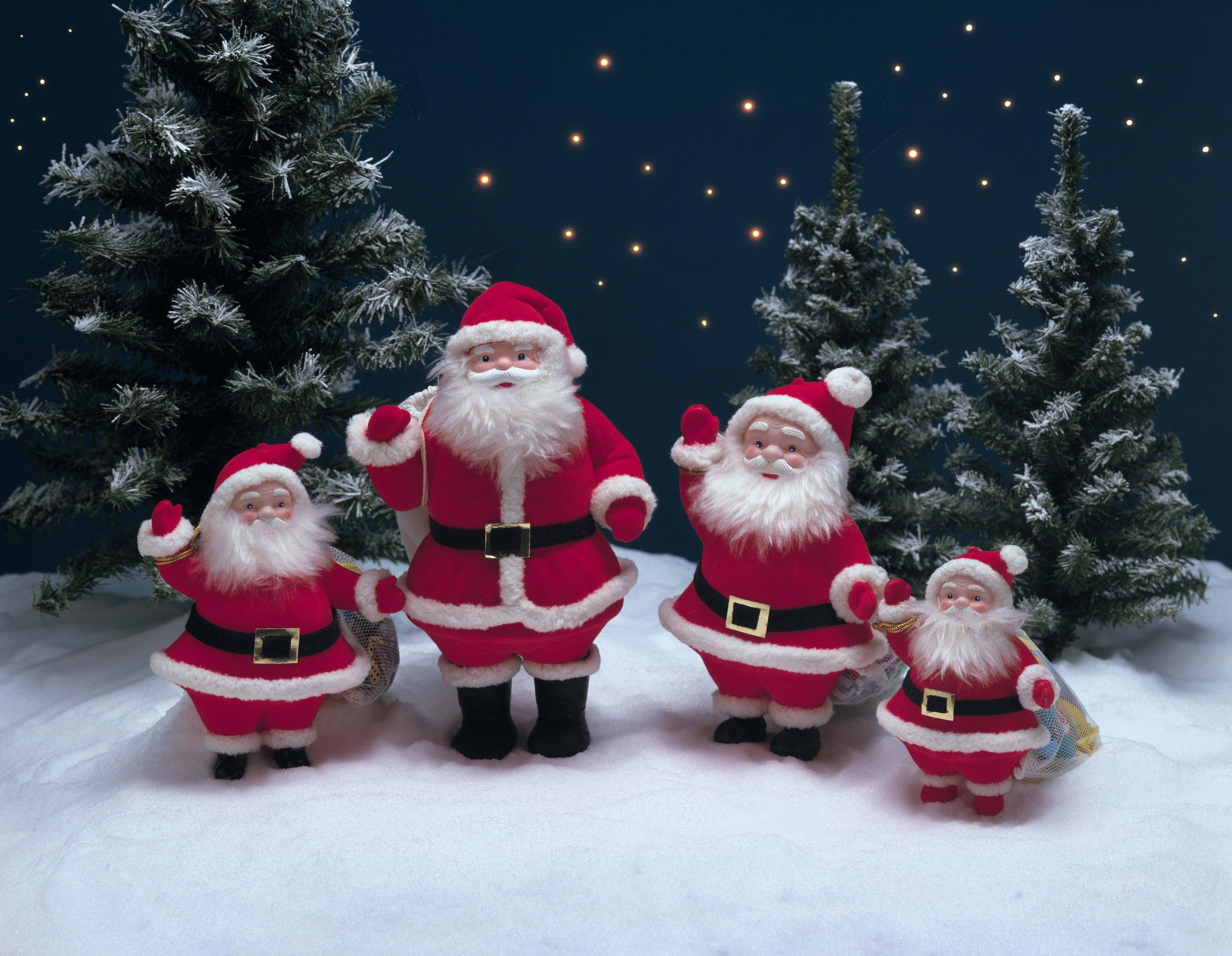 Four Santa Claus figures in a snowy forest HD Wallpaper