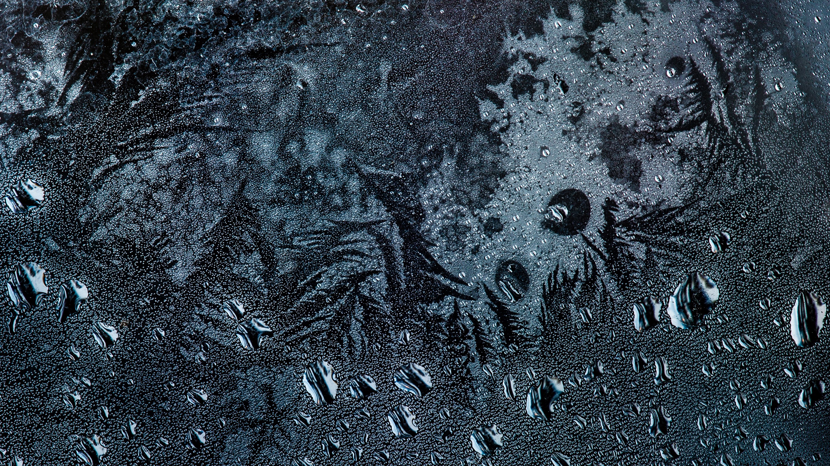 Close-up of water droplets on a dark, textured surface with frost patterns HD Wallpaper