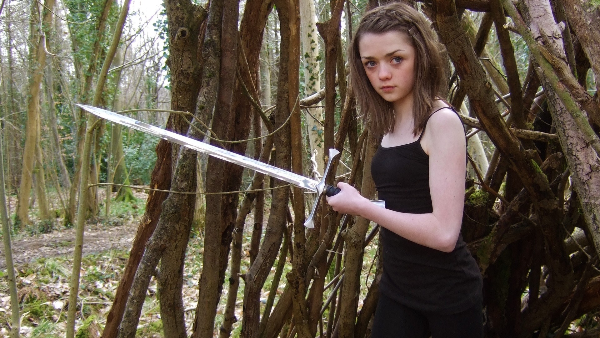 Arya Stark with a sword in the woods HD Wallpaper