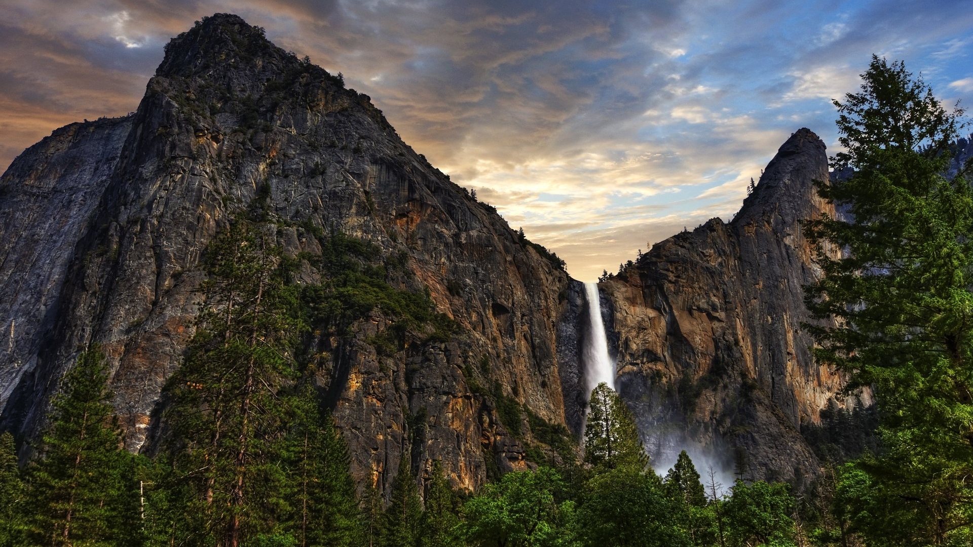 Mountain with waterfall and trees under cloudy sky HD Wallpaper