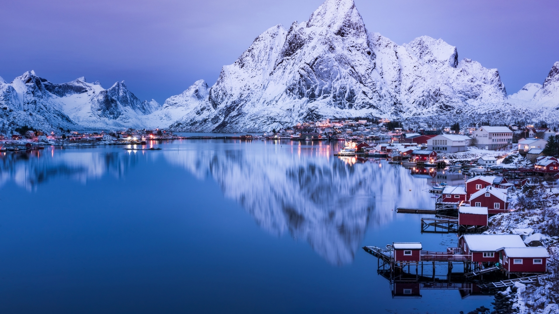 Snowy mountains and village reflected in a calm lake HD Wallpaper