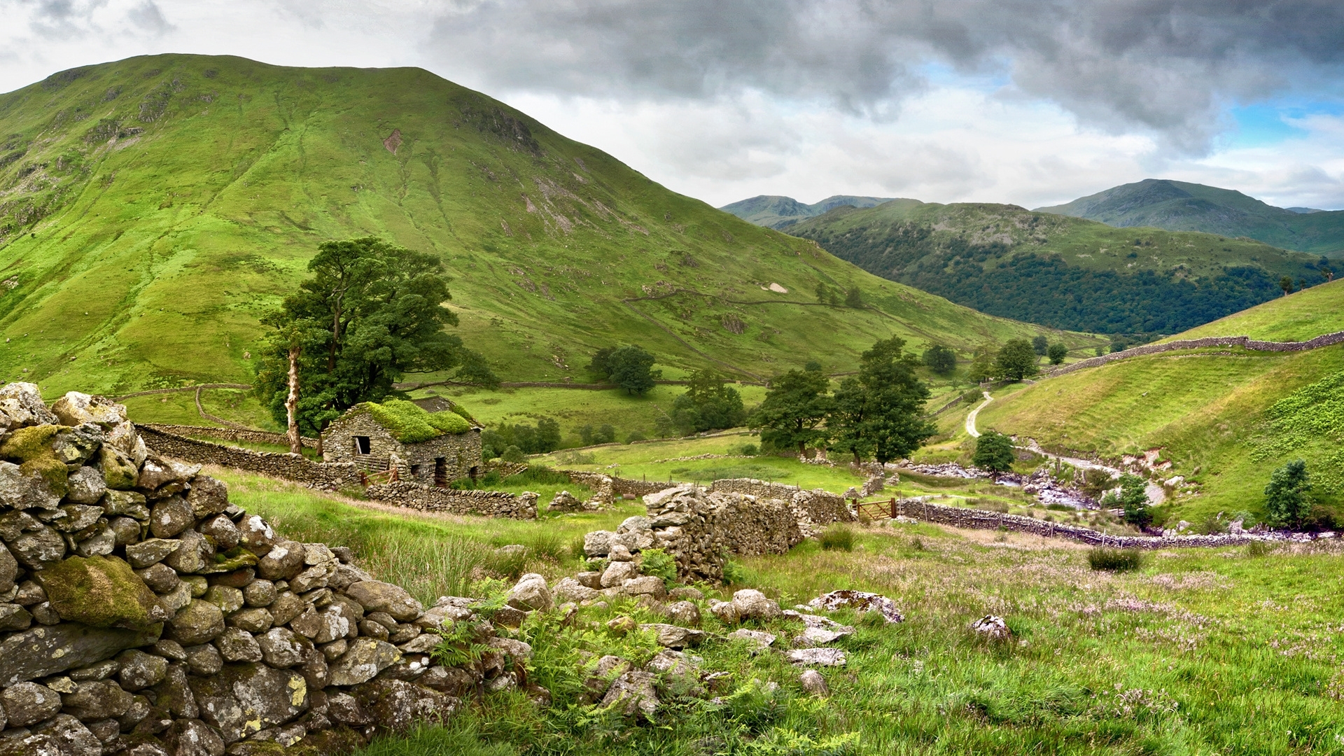 Stone cabin in a green mountain valley with stone walls HD Wallpaper